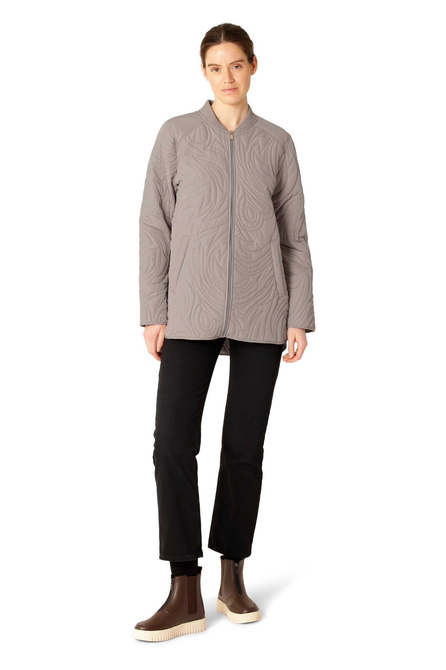 Woman wearing a gray quilted jacket and black pants on a white background