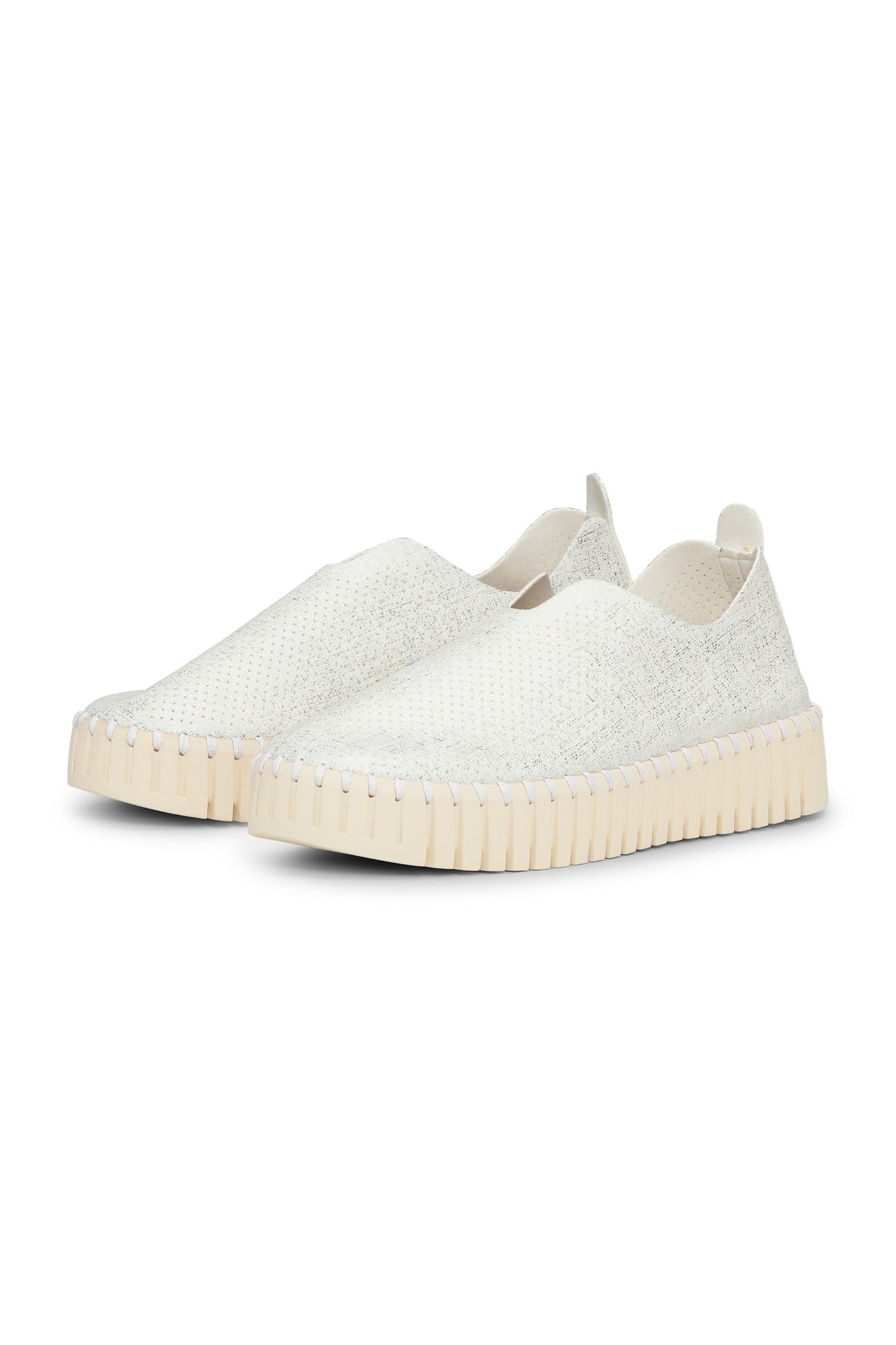 White slip-on sneakers with beige soles on a white background