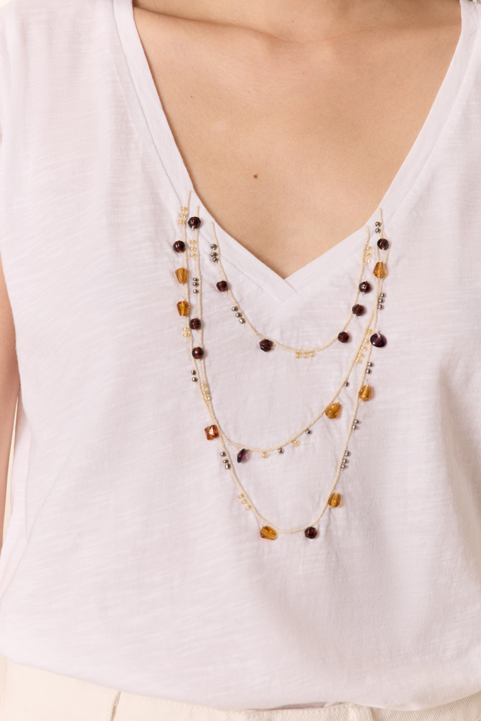 white v neck tee shirt with a layered beaded necklace print. 
