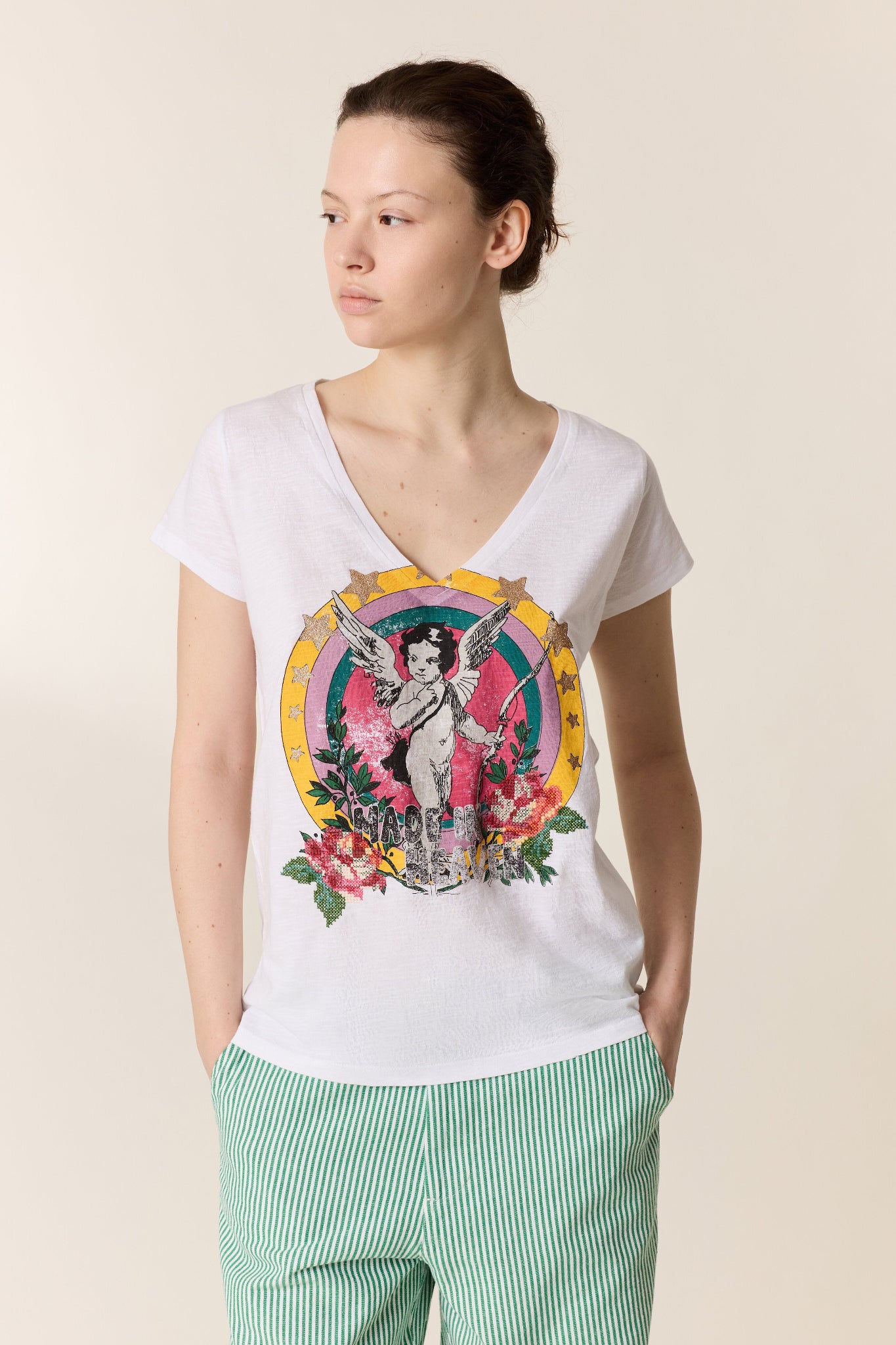 Woman wearing a white t-shirt with a colorful graphic design on a beige background