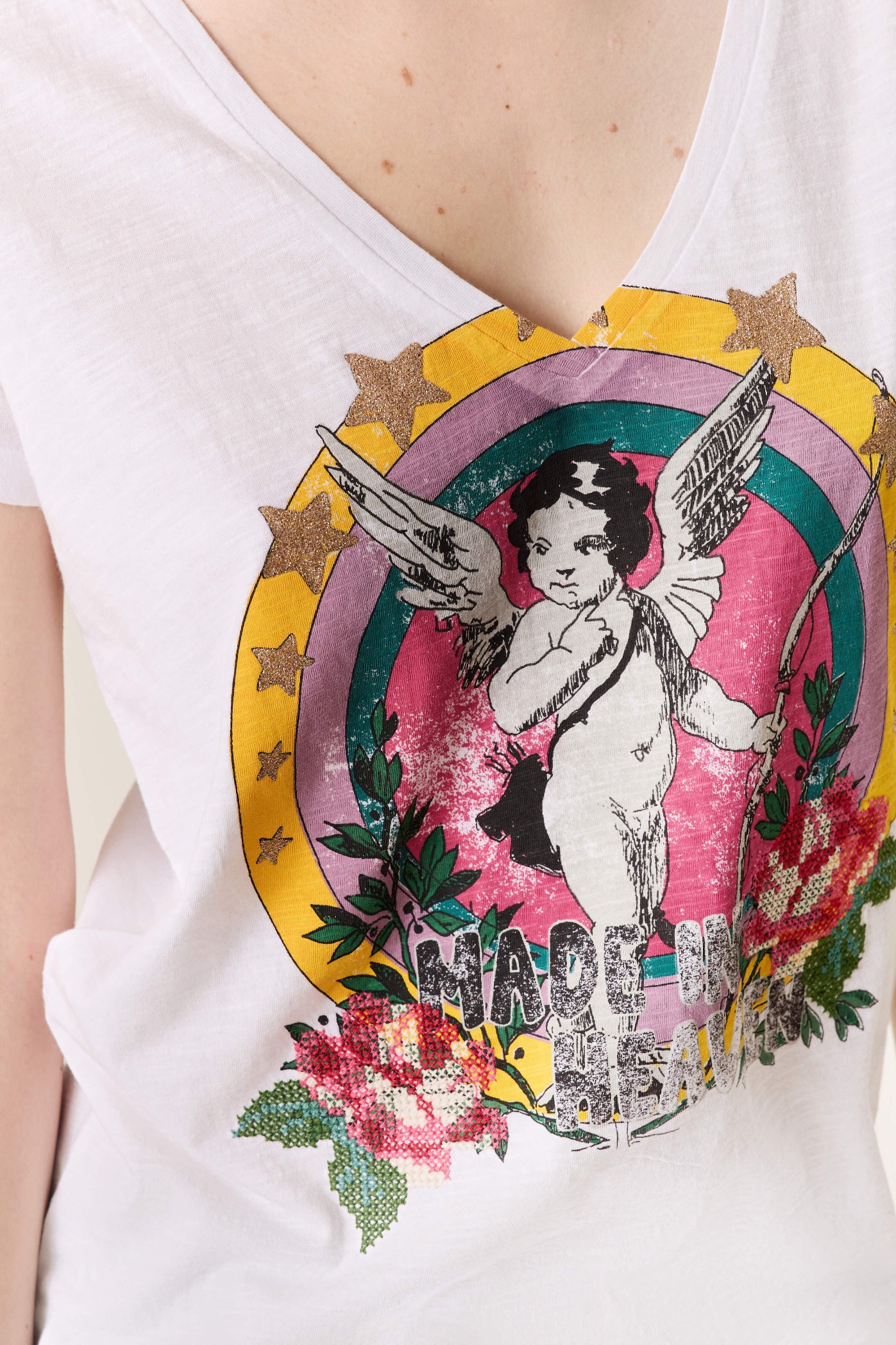 White t-shirt with a colorful graphic design featuring an angel and flowers on a white background.