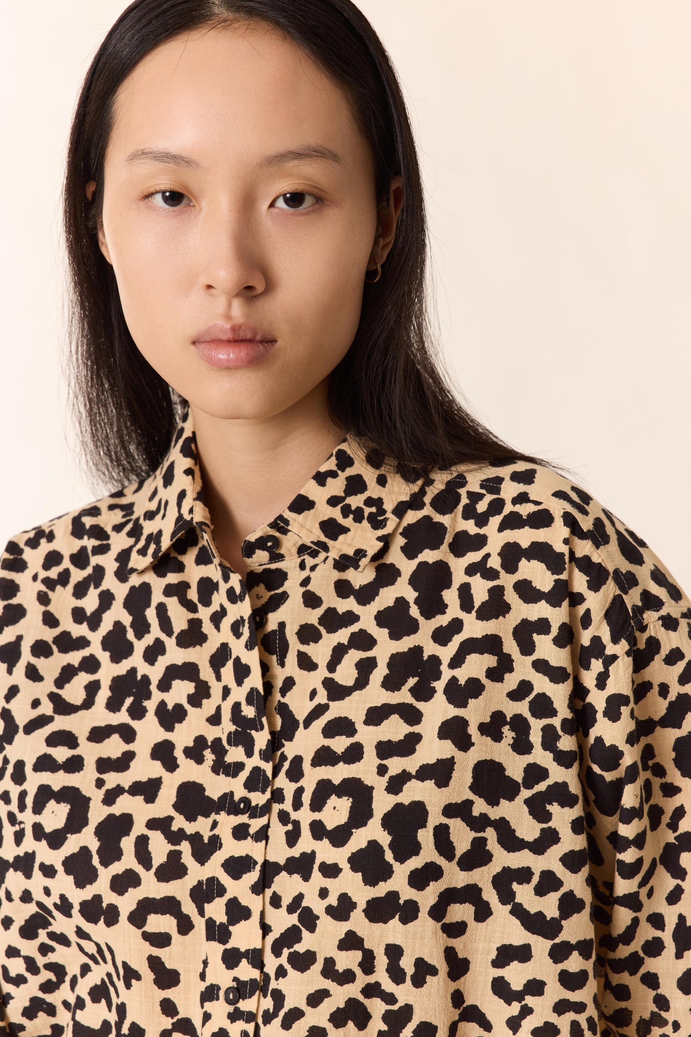 women up close wearing a leopard v neck shirt on a plain studio background. 