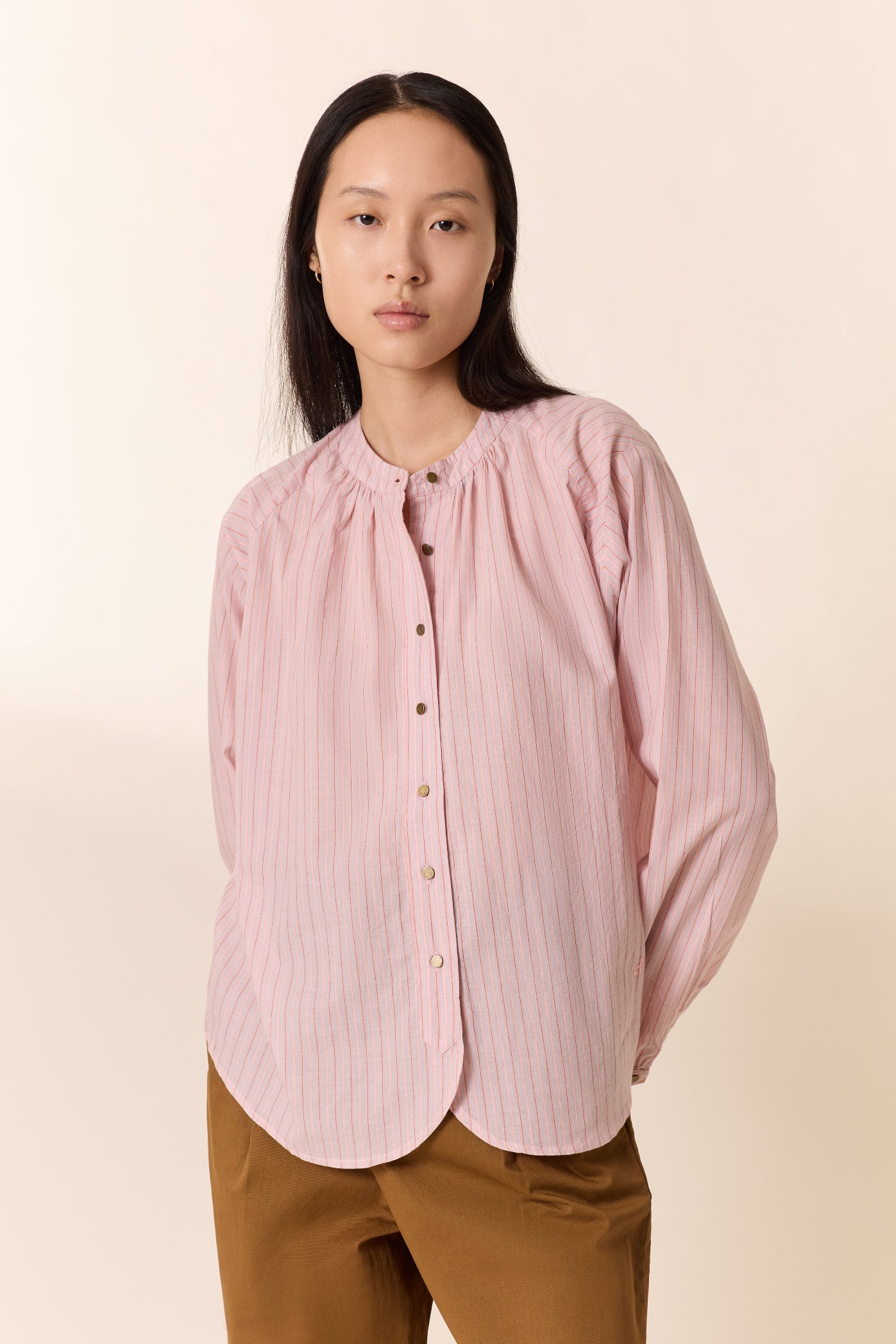 Woman wearing a pink blouse with a beige background