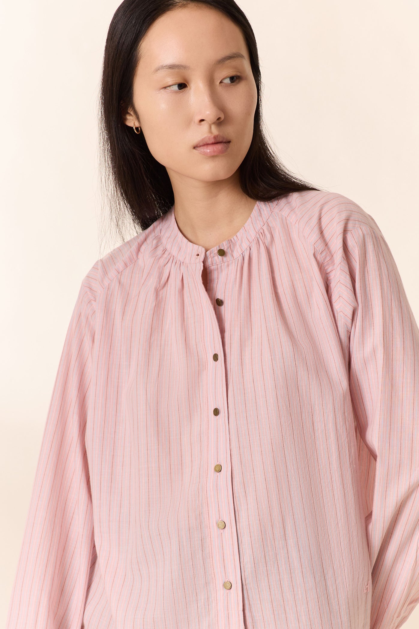 Woman wearing a light pink blouse with a plain background