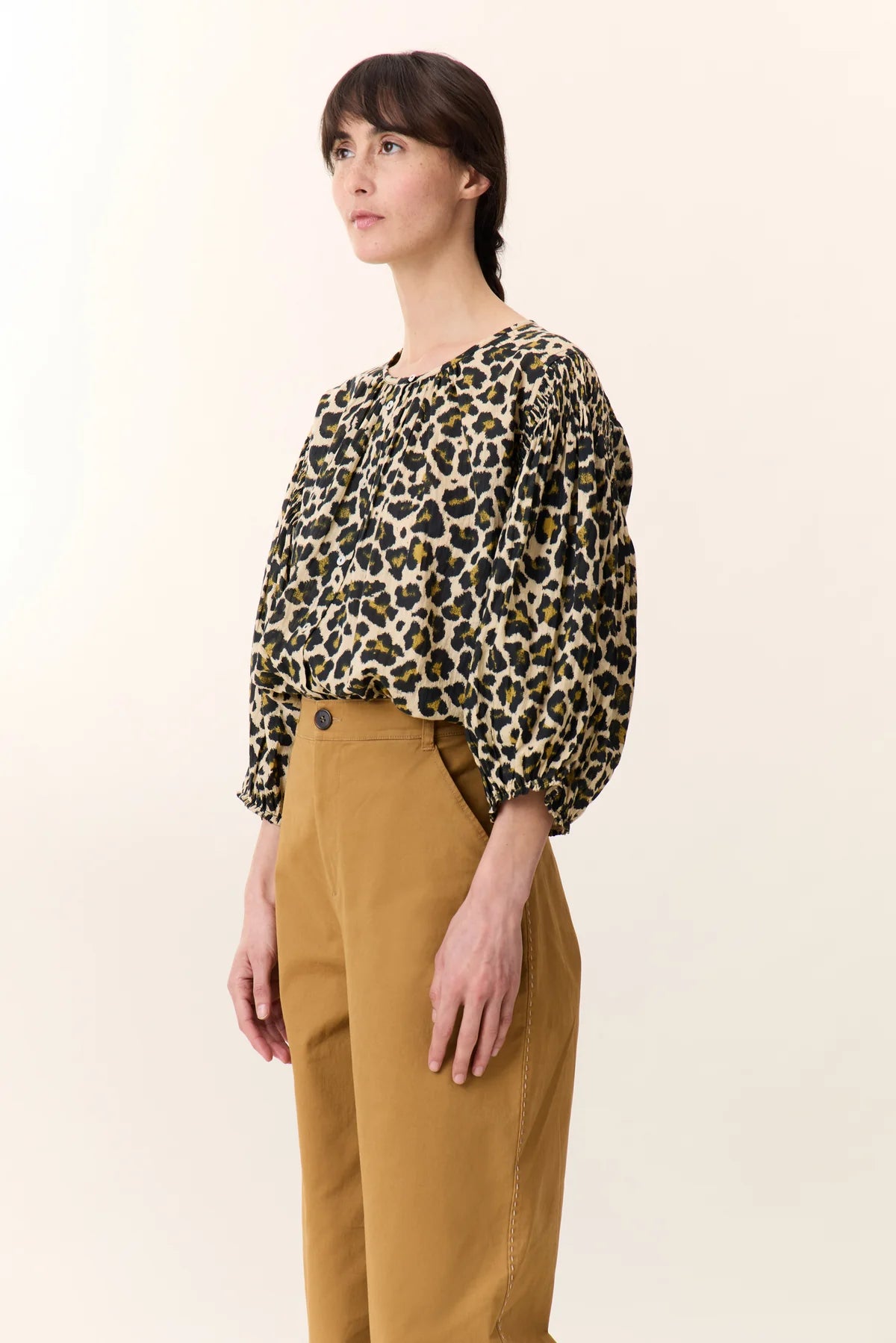 Model wearing leopard print blouse with a button detail  and balloon sleeves on a plain background
