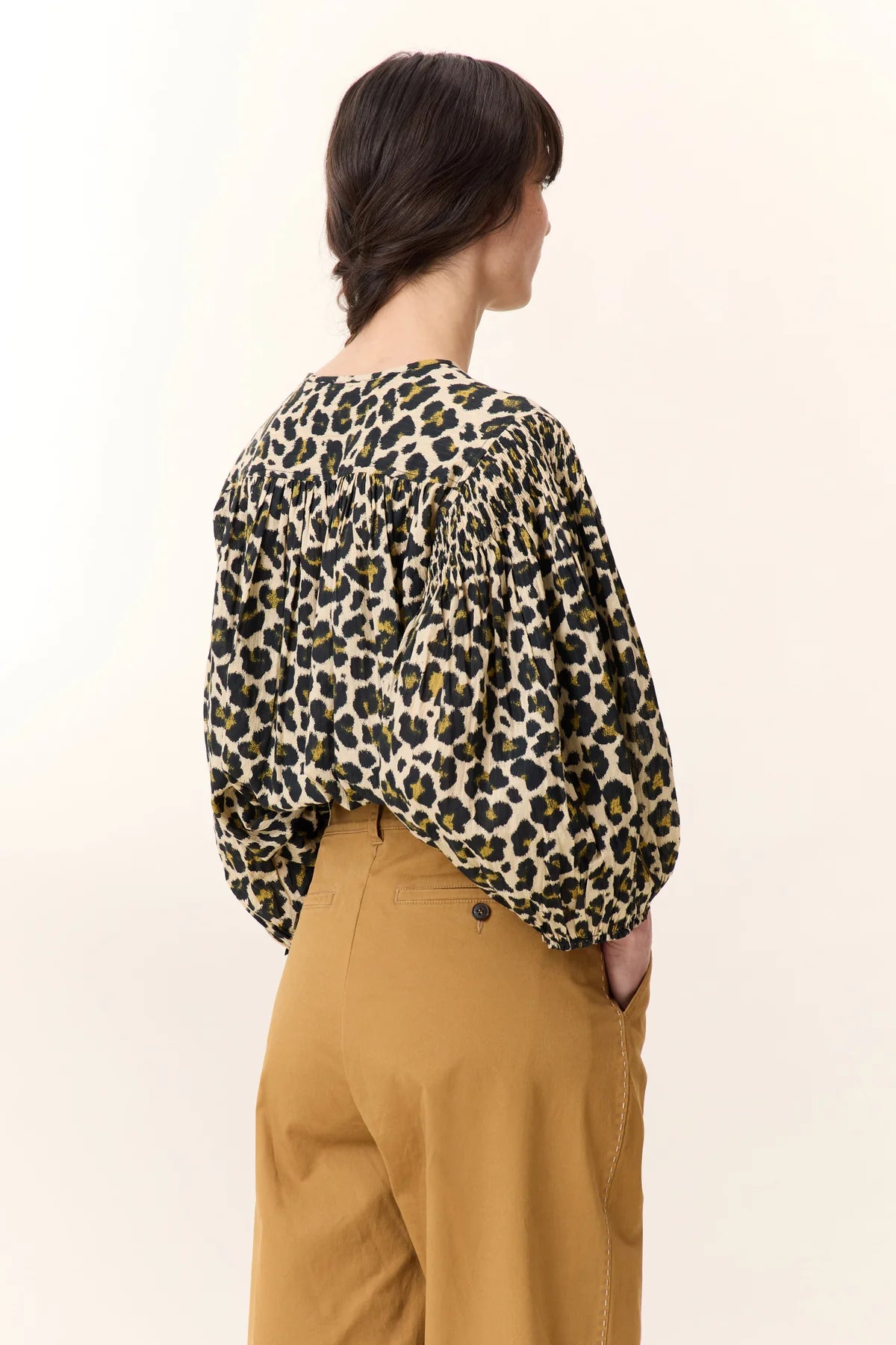 Model wearing leopard print blouse with a button detail  and balloon sleeves on a plain background