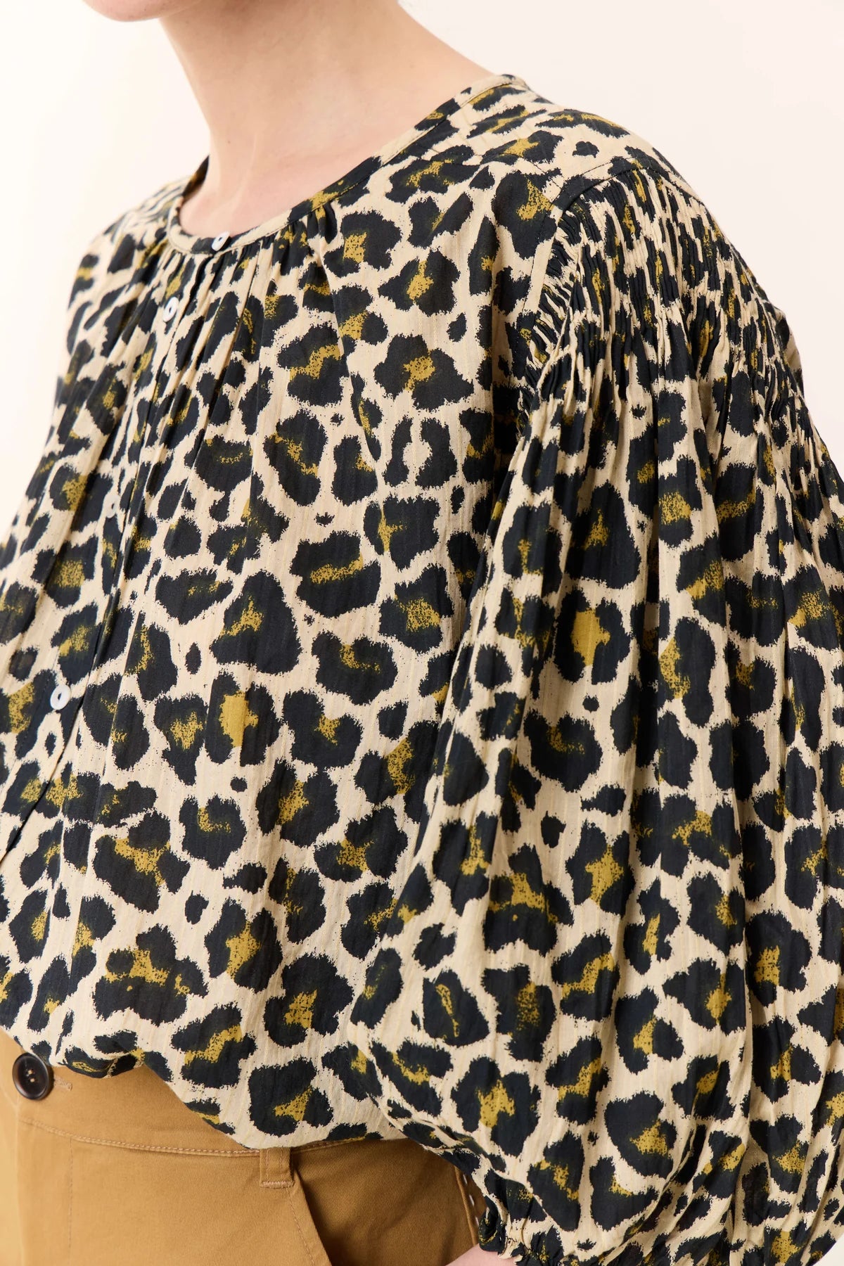 Leopard print blouse with a button detail on a plain background
