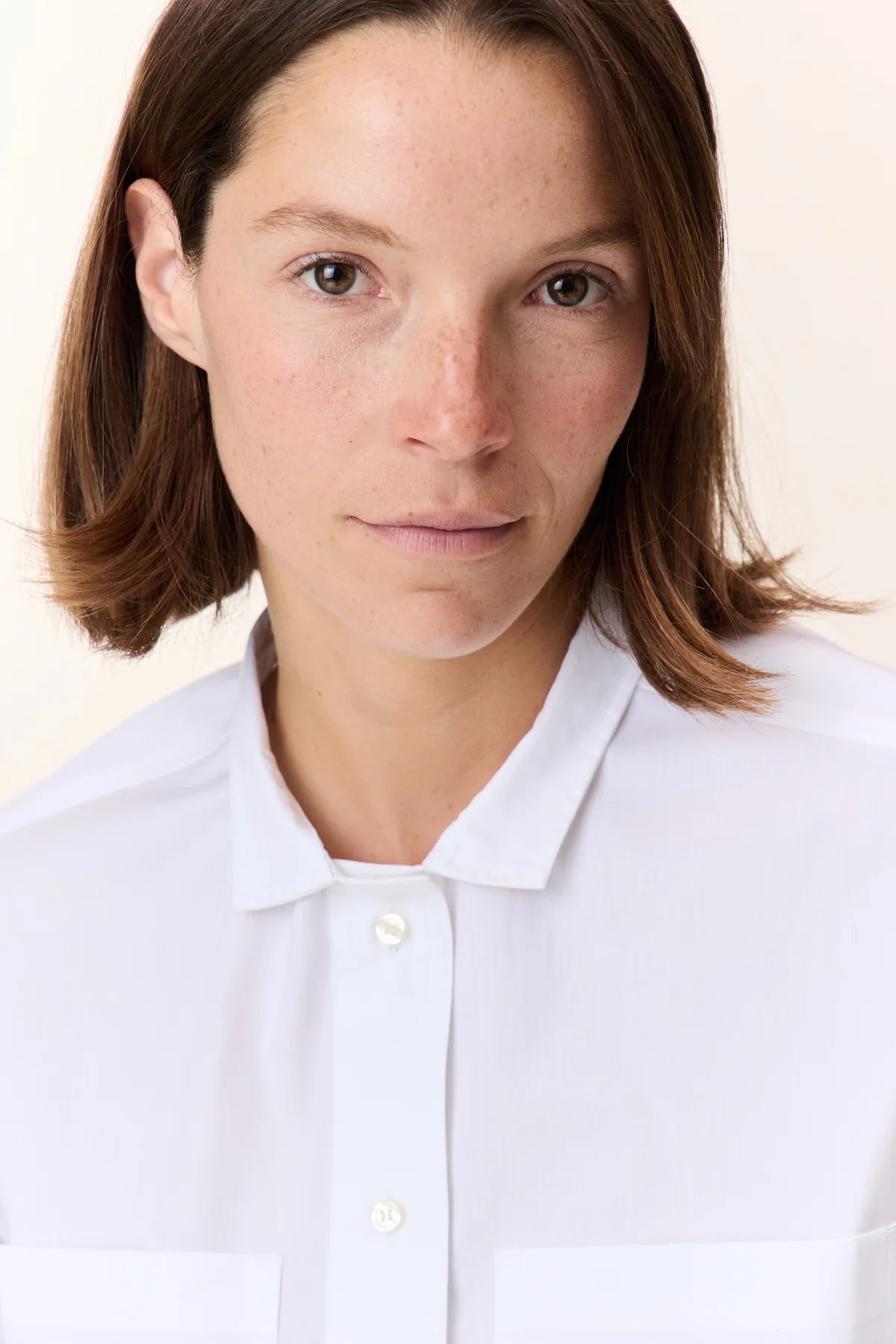 Person wearing a white shirt with mandarin collar against a plain background