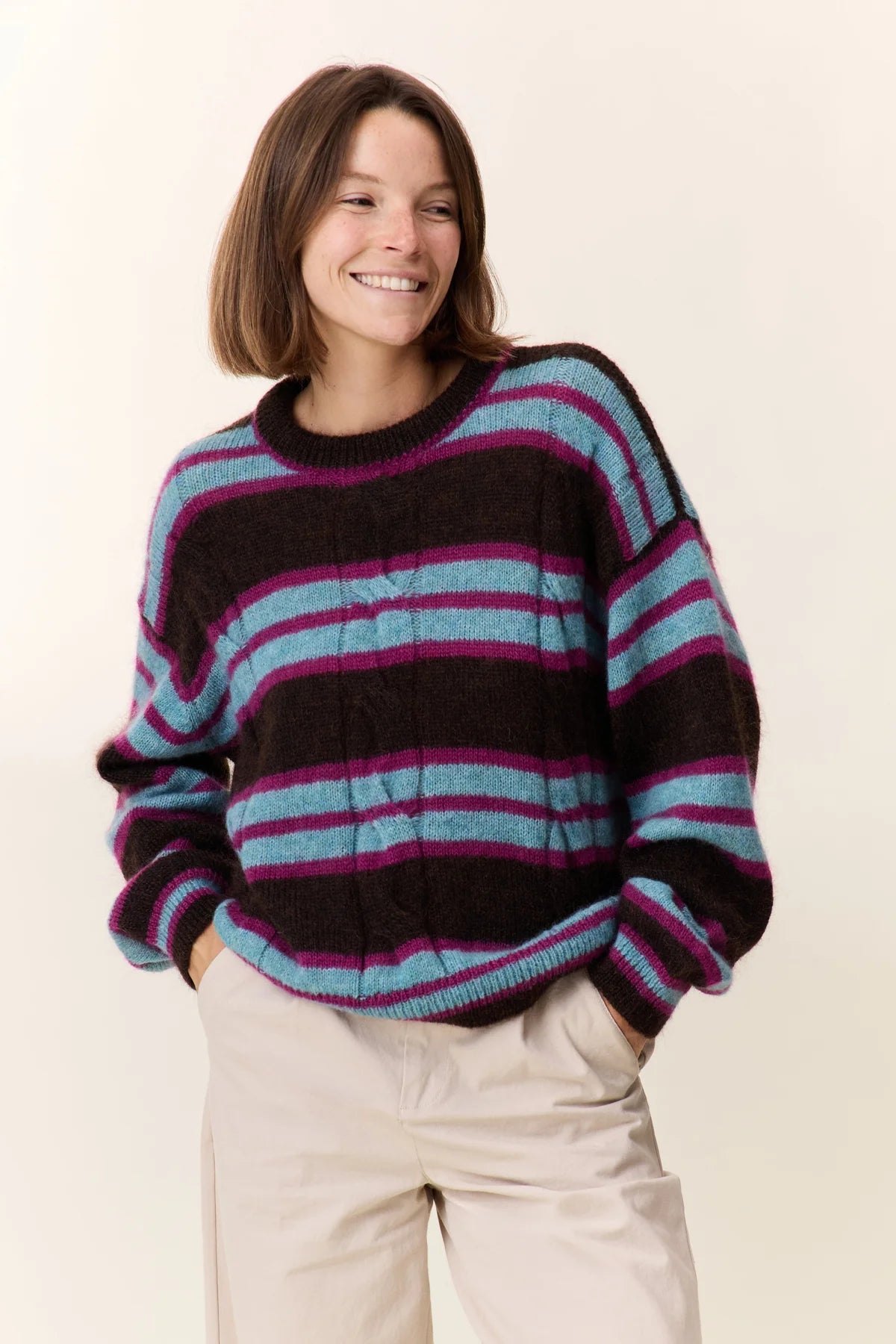 Person wearing a striped sweater with a plain background