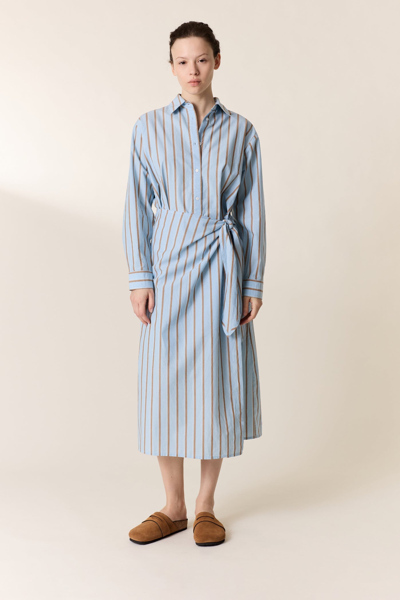 Woman wearing a blue and white striped dress on a beige background