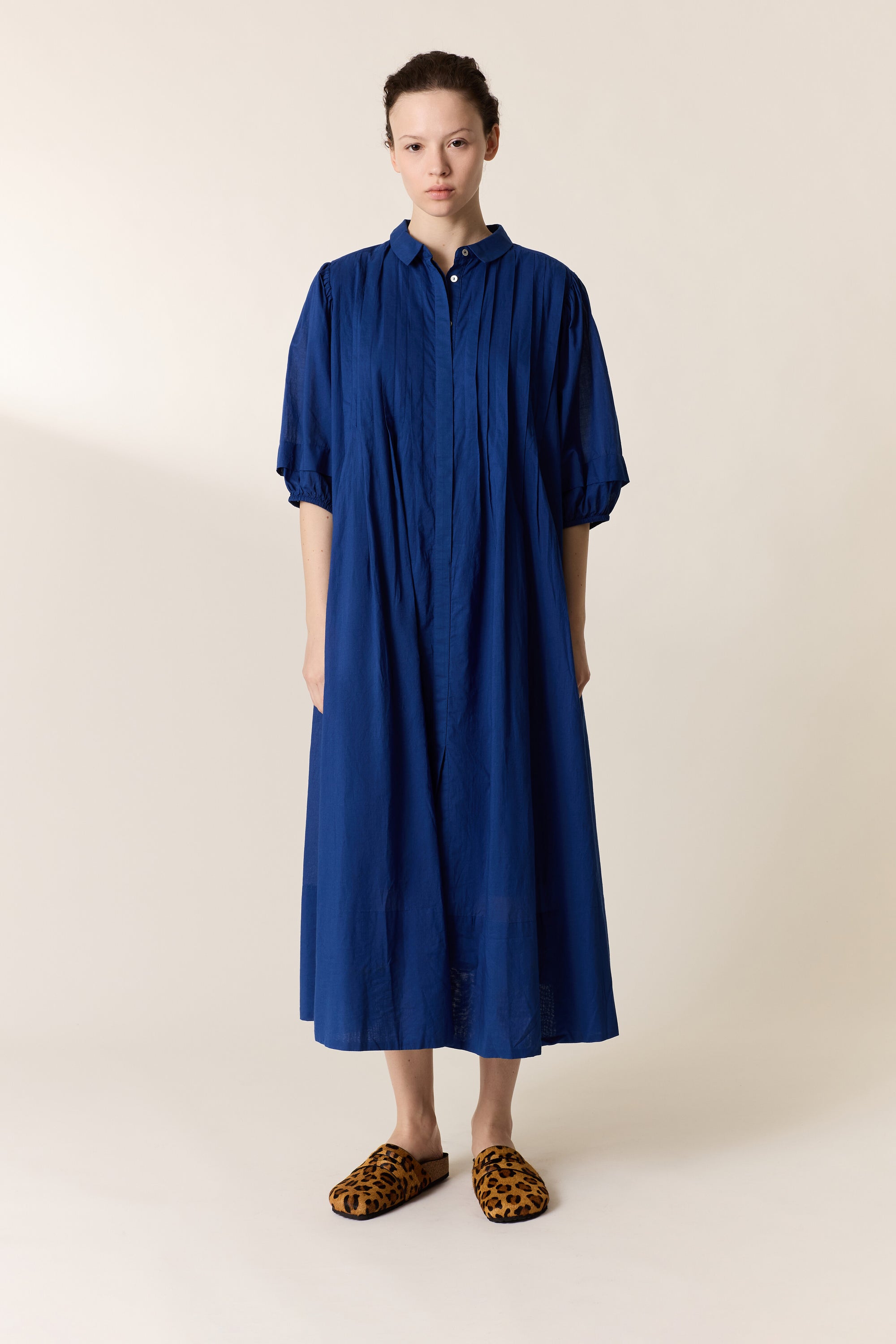 Women wearing a blue pleated dress on a plain background