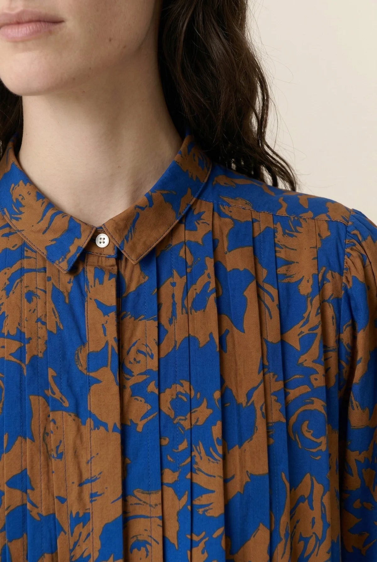 Women wearing a floral print midi dress up close to show button detail on collar  on a plain background. 