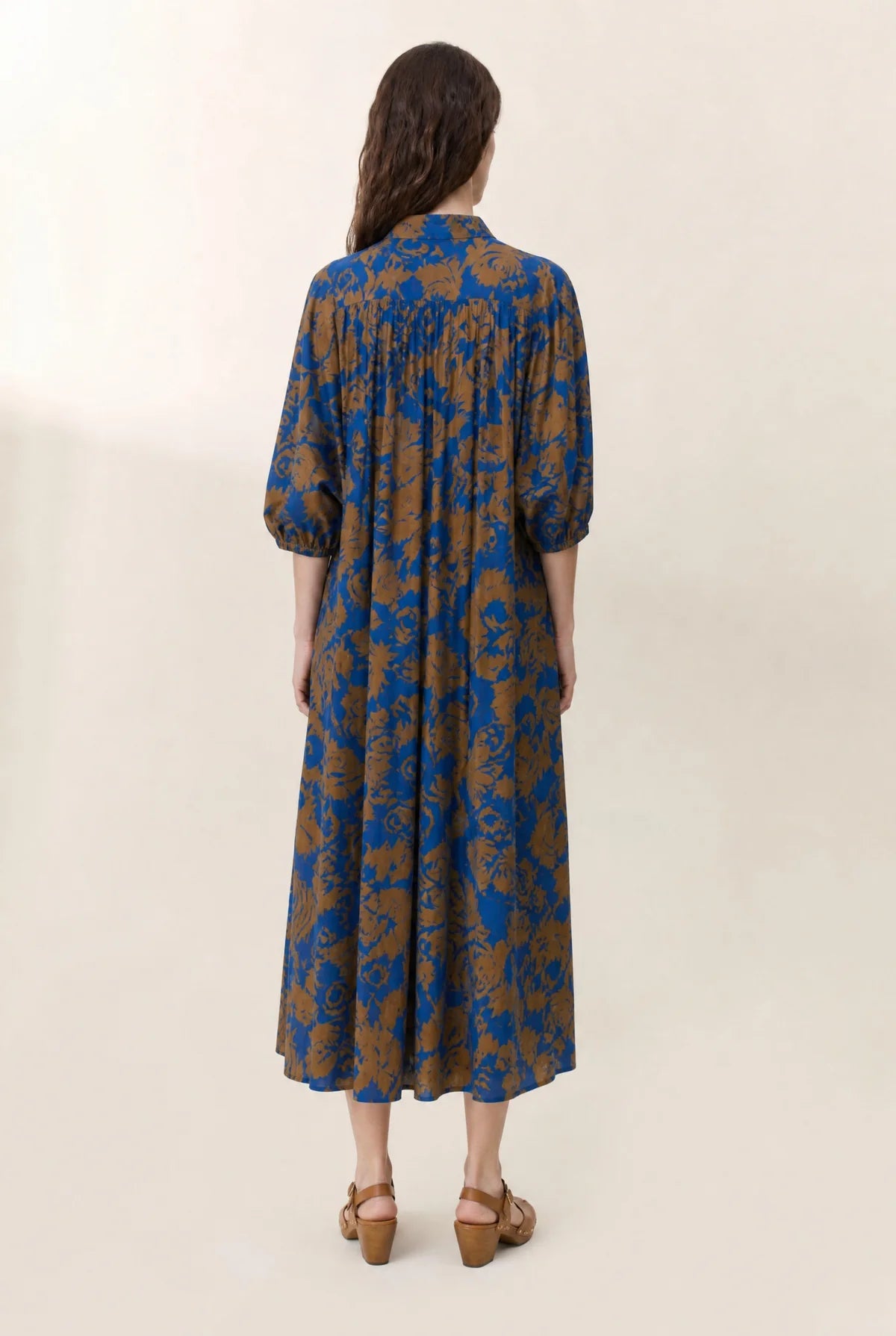 Women wearing a floral print midi dress shown from the back on a plain background. 
