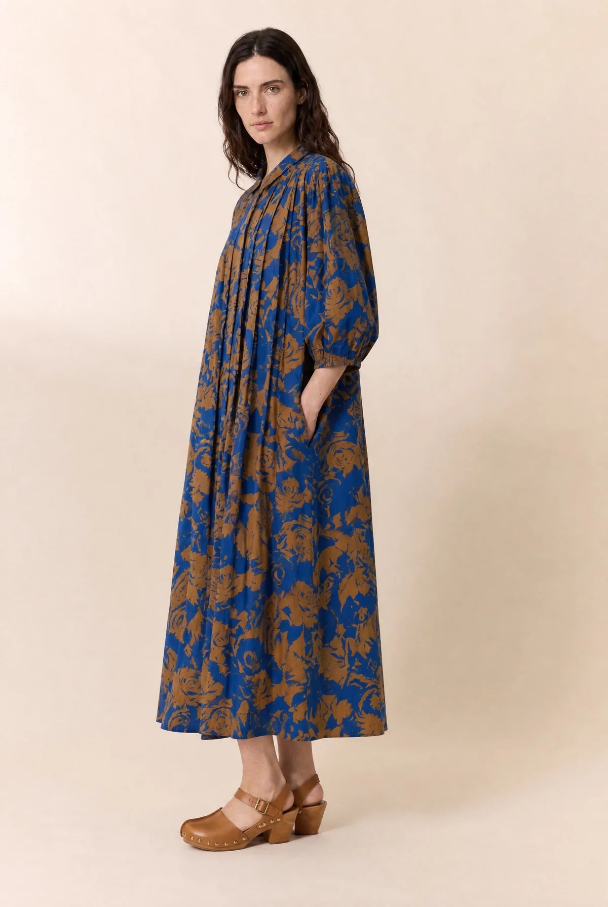 Women wearing a floral print midi dress shown from the side on a plain background. 