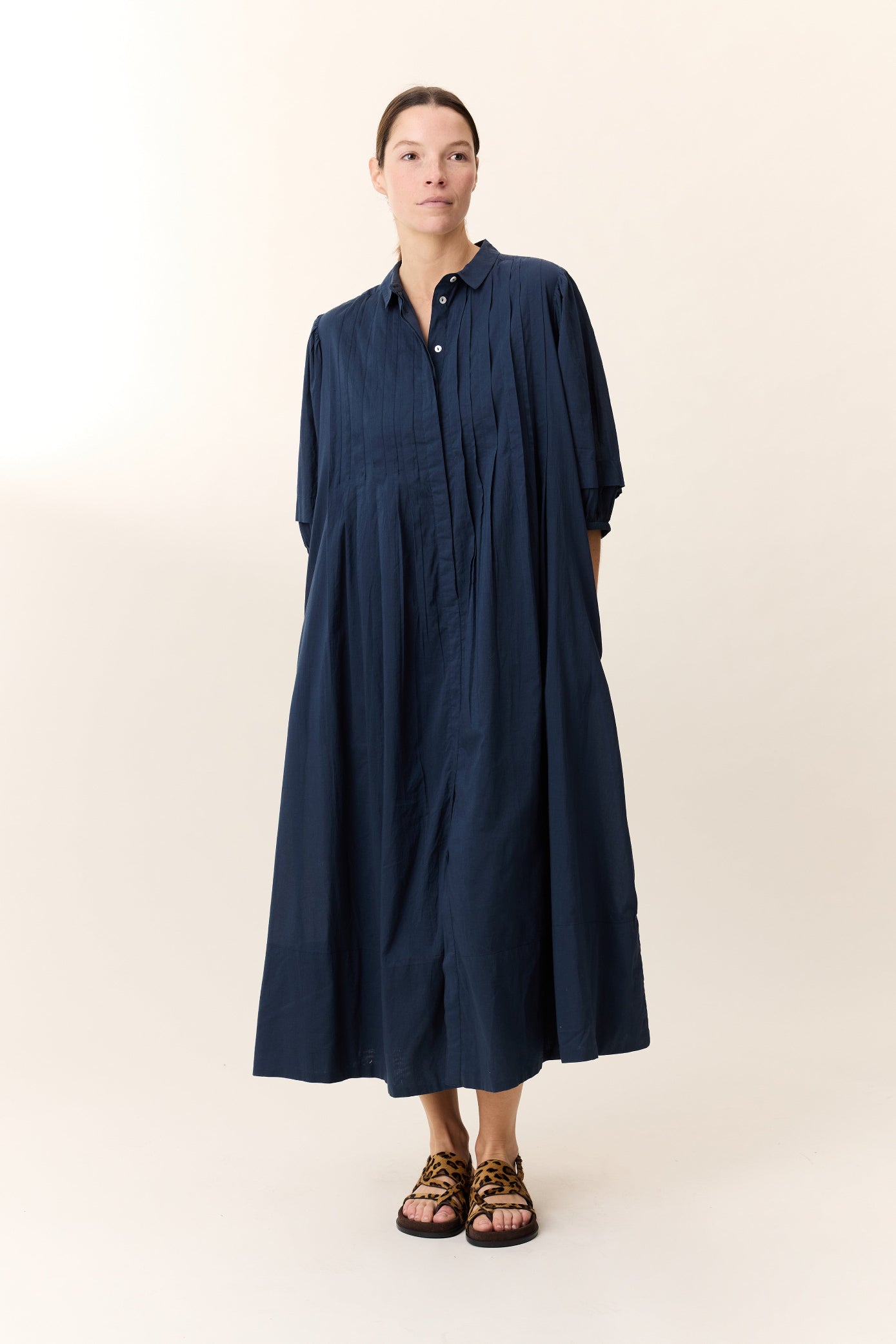 Model wearing midi dress in navy  with puff sleeves and frill detail on a white background