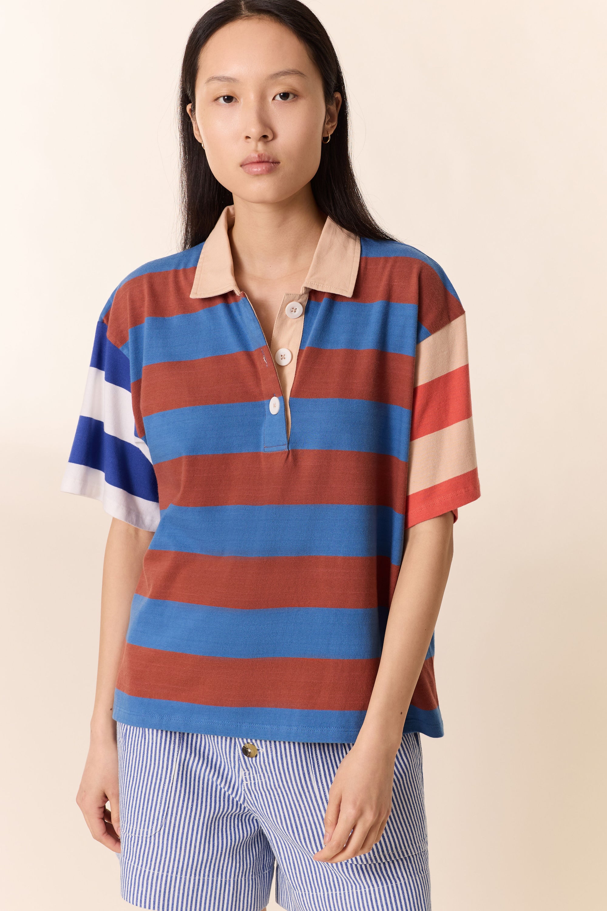 Woman wearing a striped polo shirt with a beige background