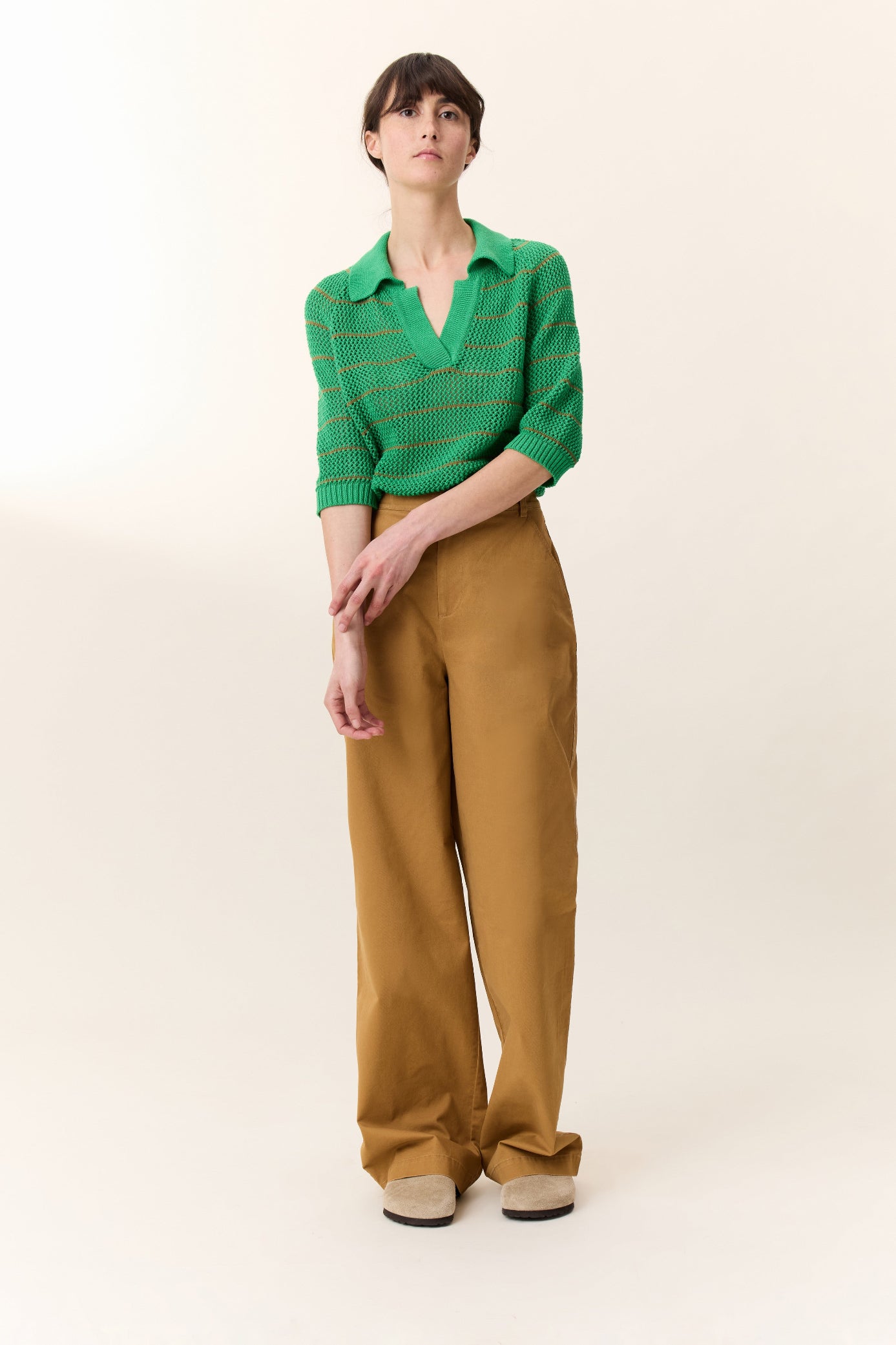 Woman wearing a green shirt and brown pants on a white background