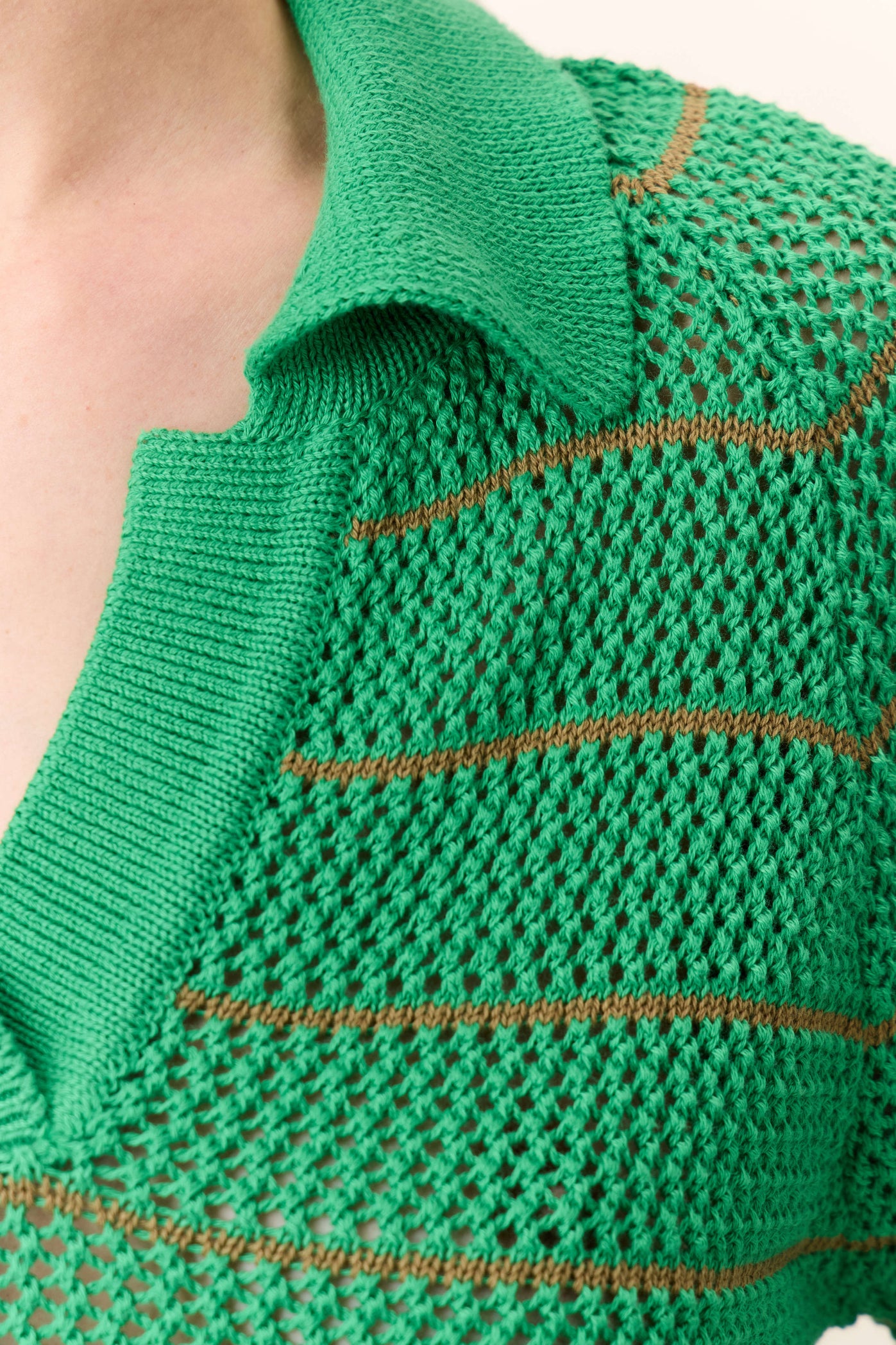 Close-up of a green knitted garment with brown stitching