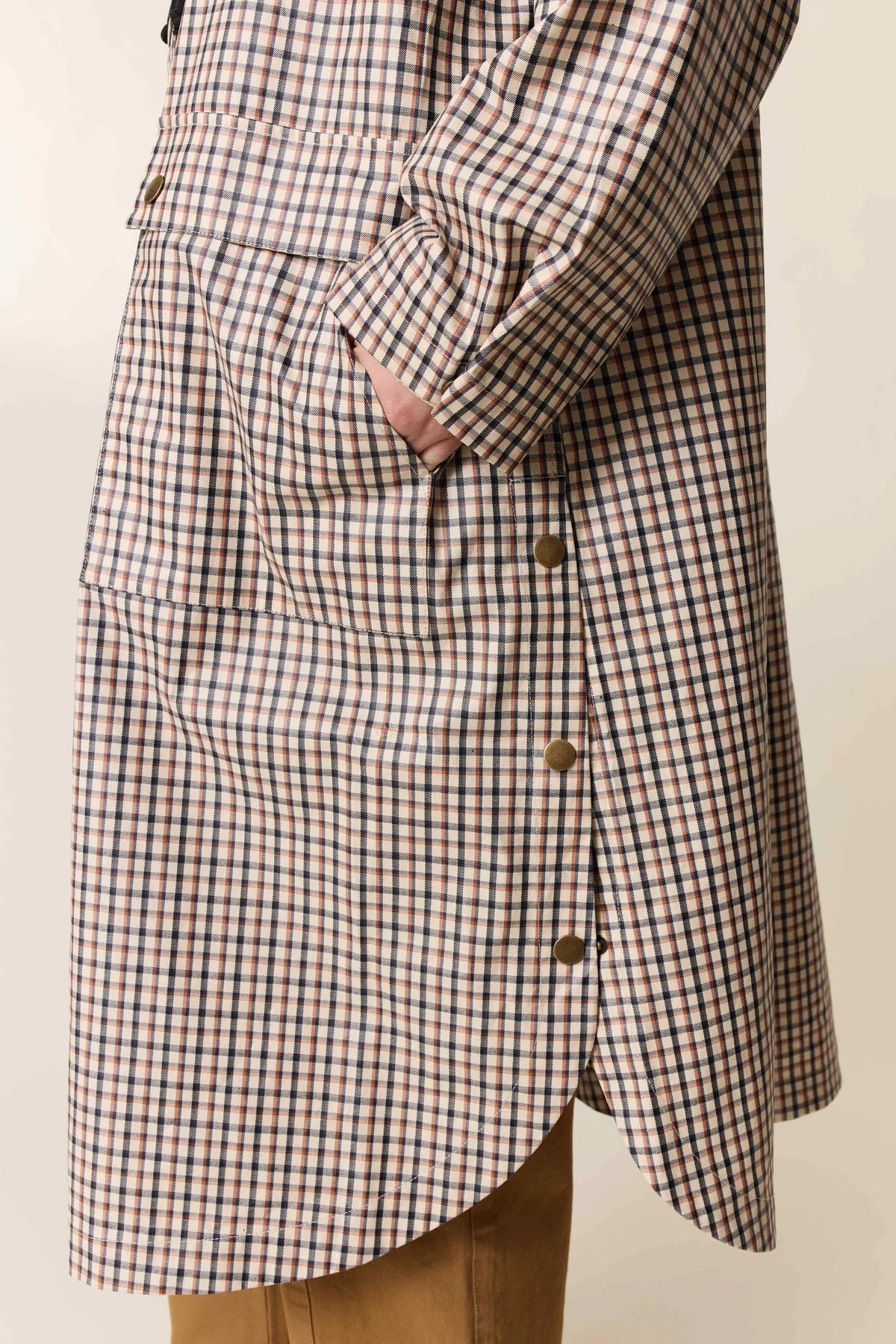 Checkered coat with gold button details on a neutral background