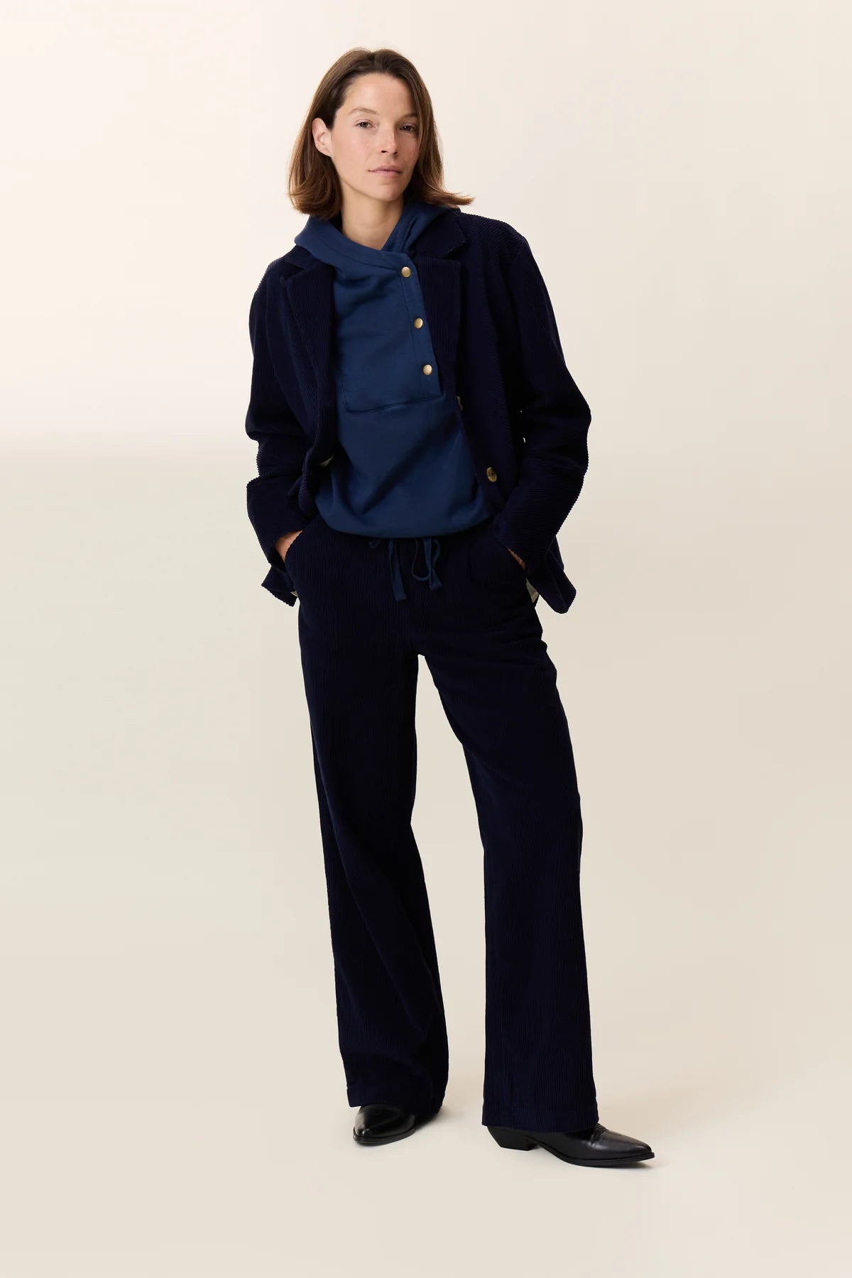 Person wearing a navy blue jacket and pants on a beige background