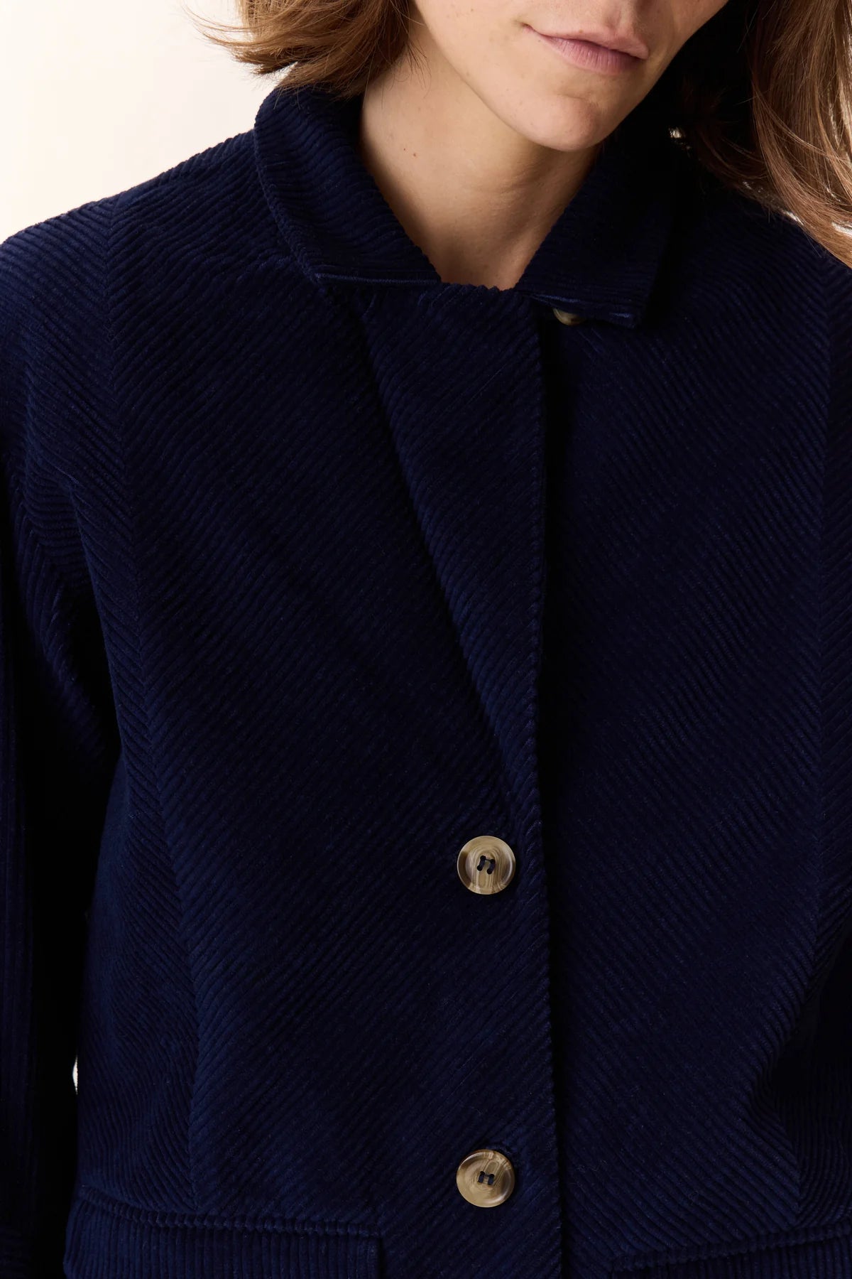 Navy blue textured jacket with gold buttons on a neutral background