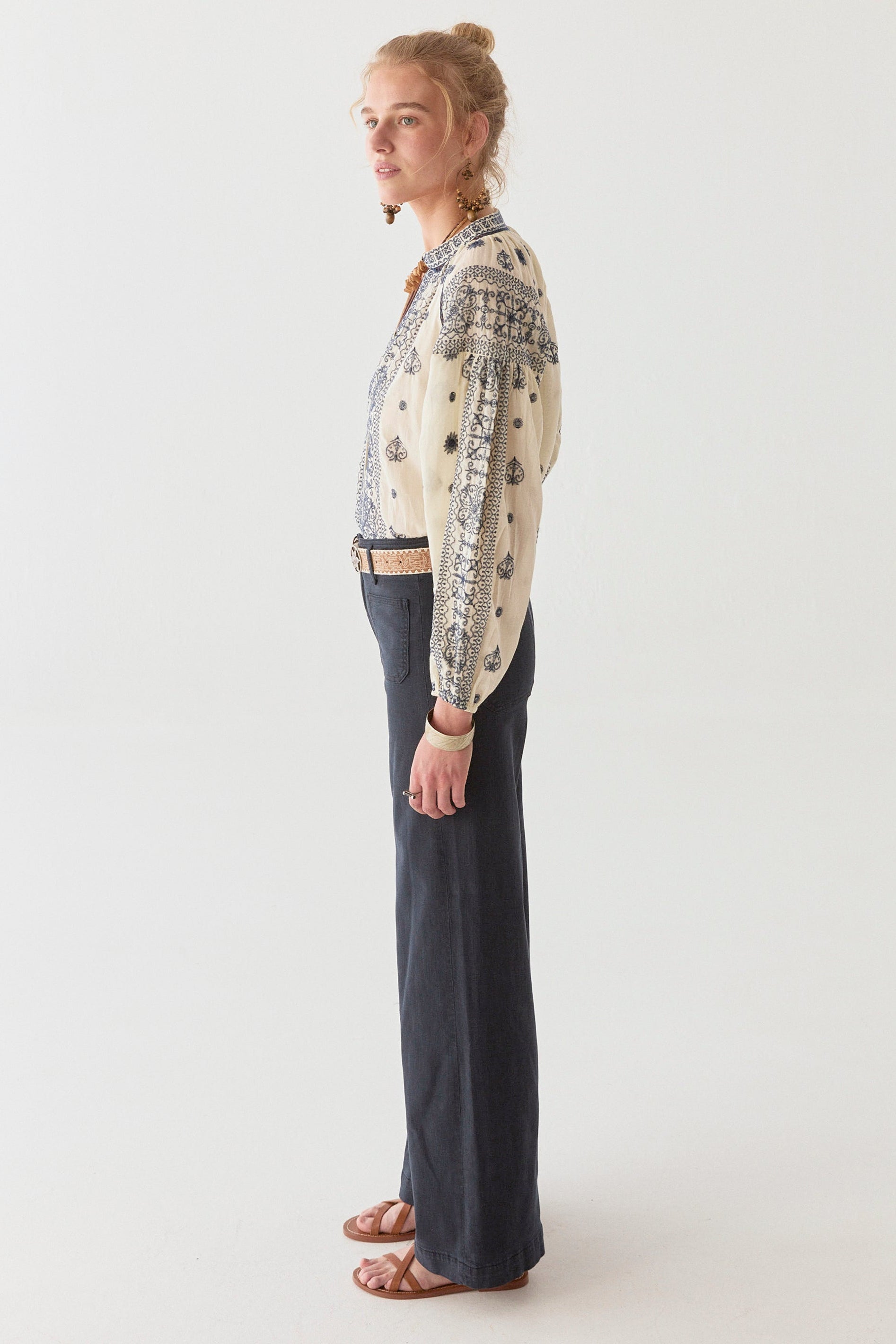 Model wearing navy wide leg pant and cream and navy cotton blouse on a white background.  Paired with tan sandals. 