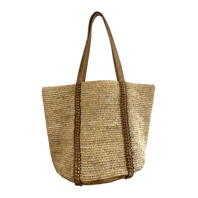 Woven straw natural coloured tote bag with a brown leather handle on a white background