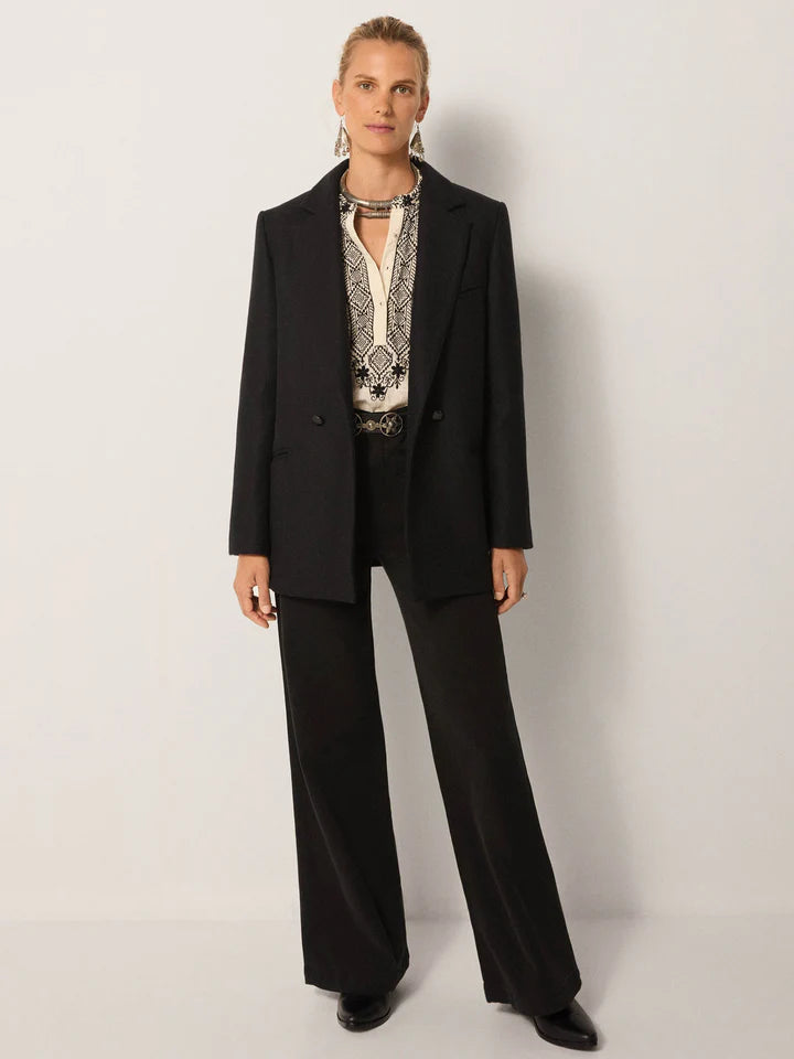 Woman wearing a black suit with a patterned blouse against a white background