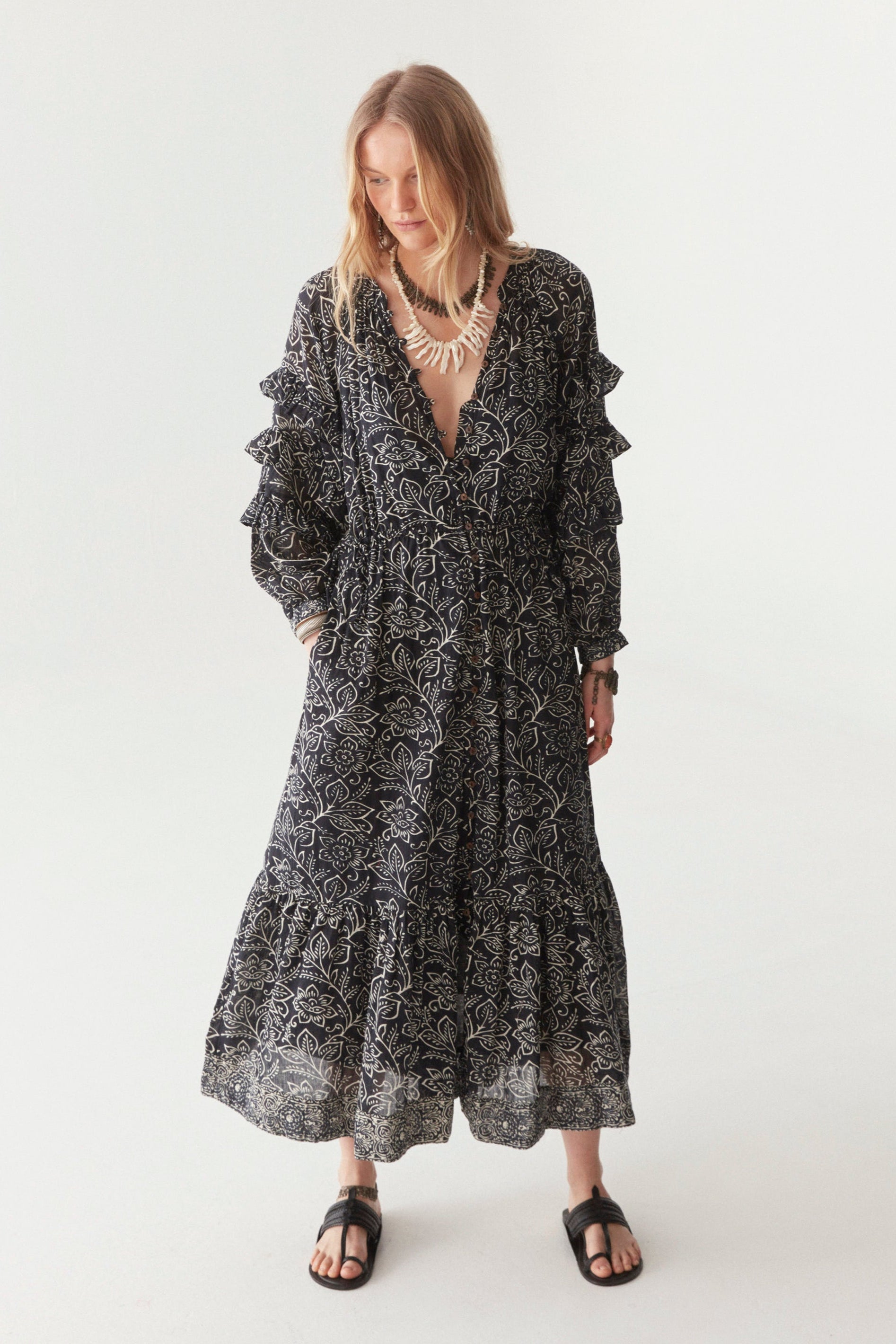 Woman wearing a black and white floral patterned maxi dress against a white background.