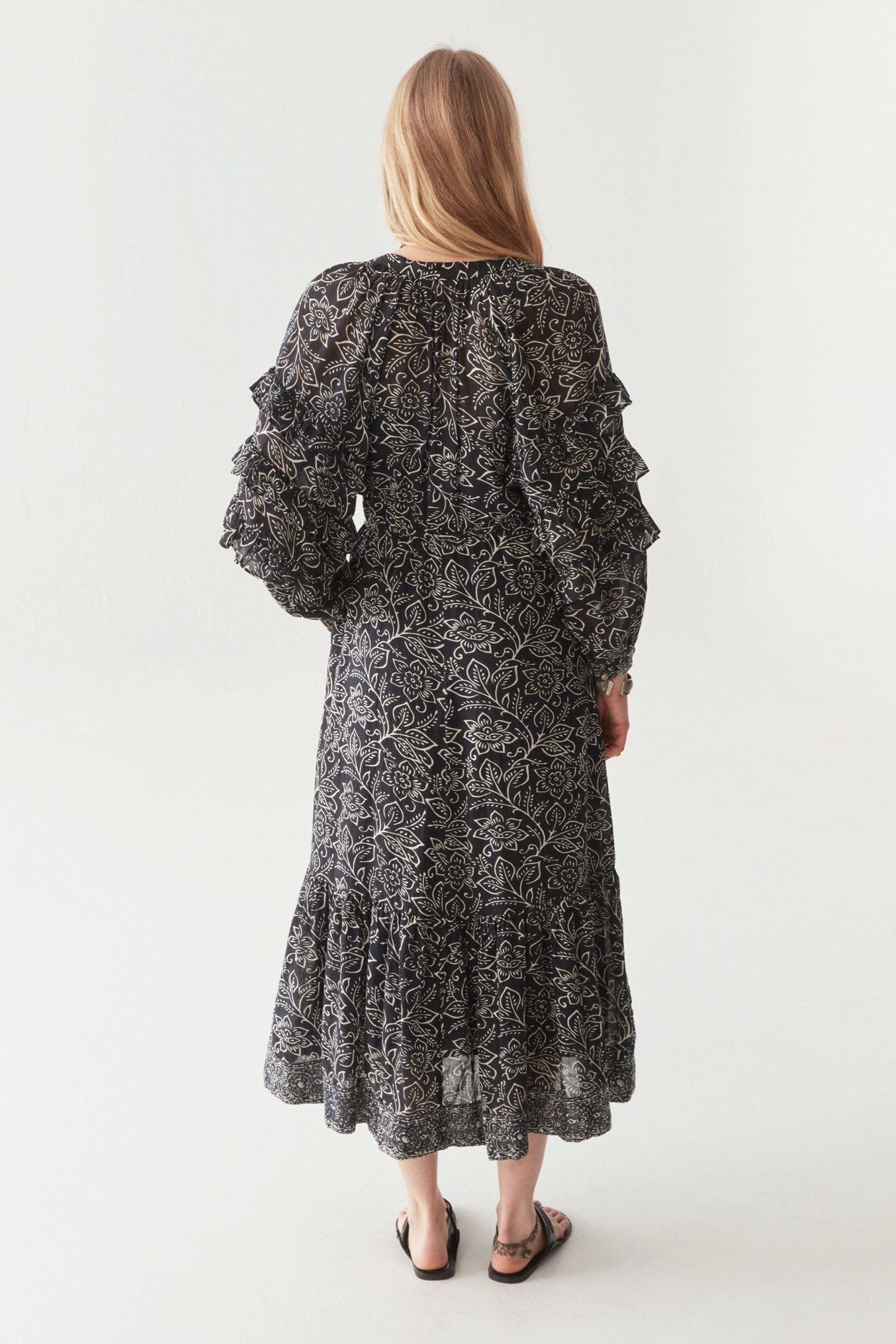 Woman wearing a black and white floral patterned maxi dress against a white background.