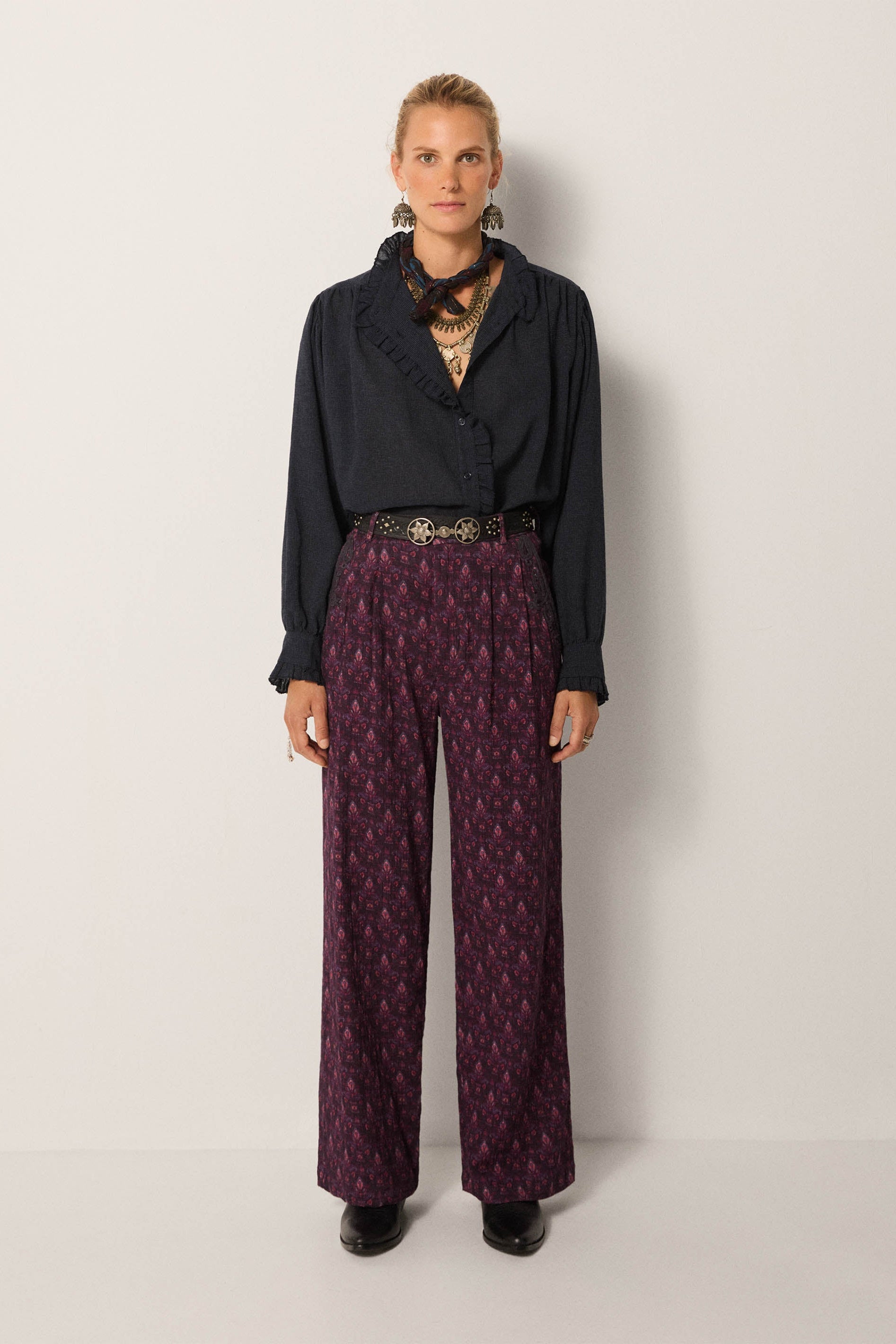 Person wearing a black top and patterned purple pants on a white background