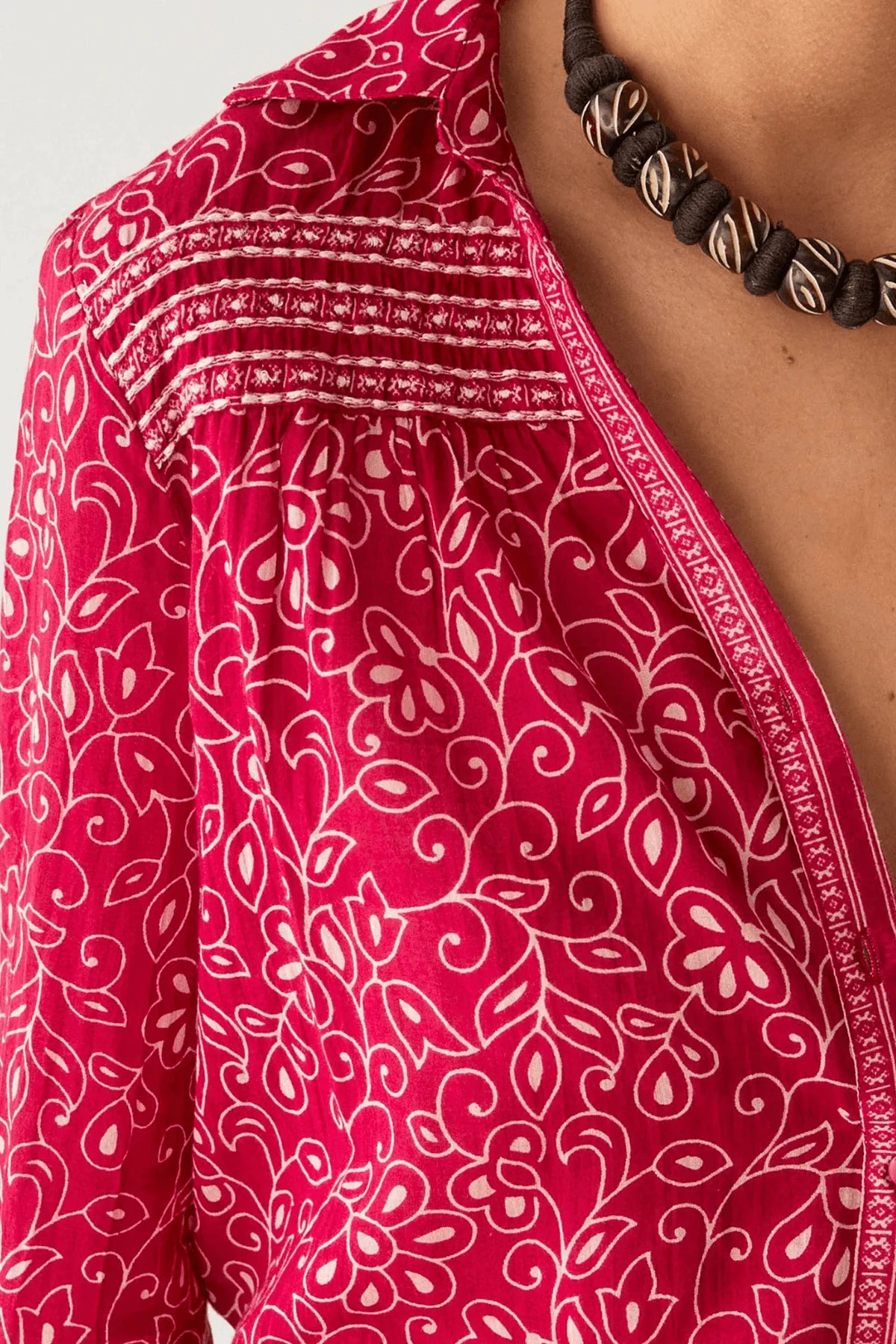 Up close view of person wearing a red and white floral patterned shirt with a white background
