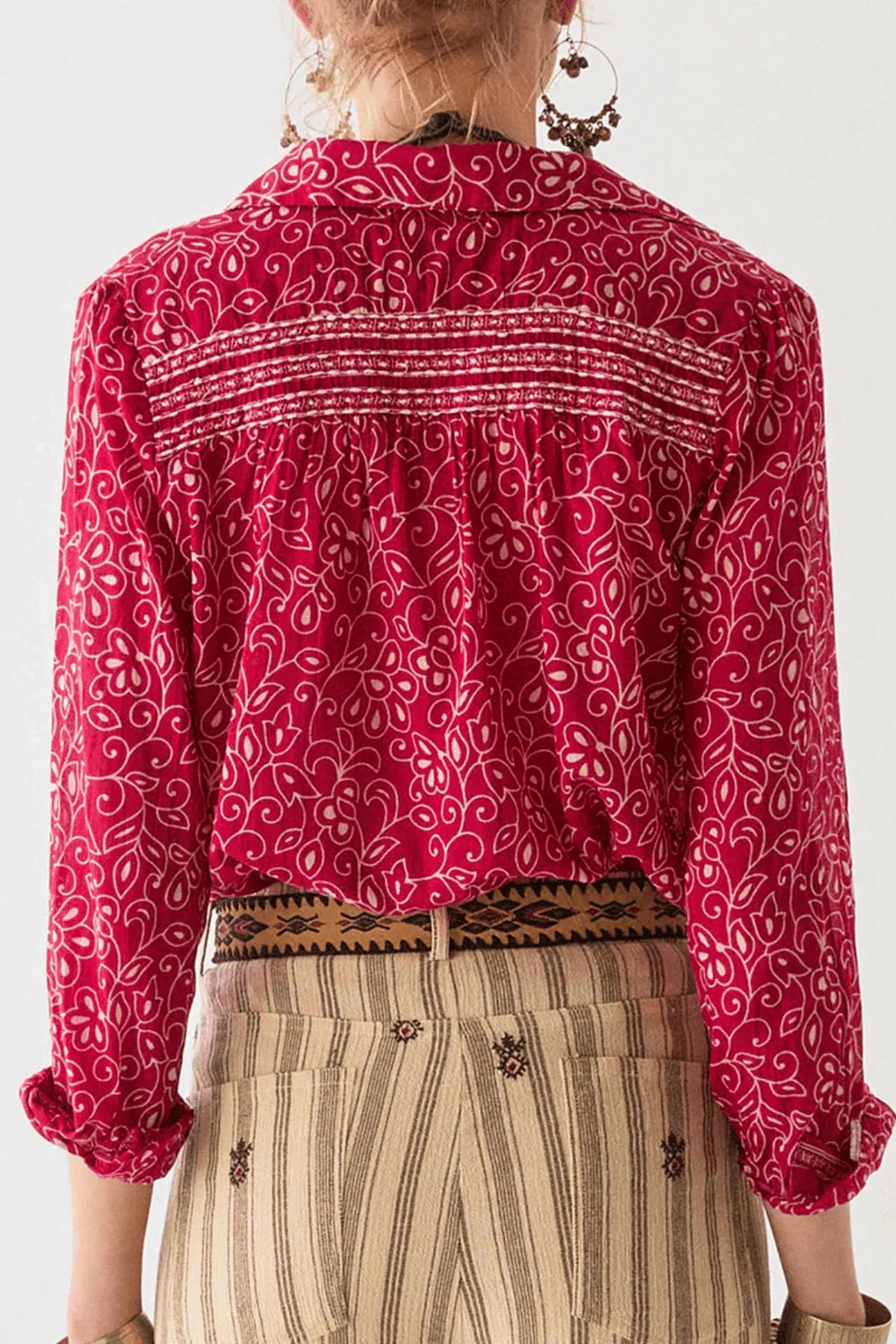Person wearing a red and white floral patterned shirt with a white background