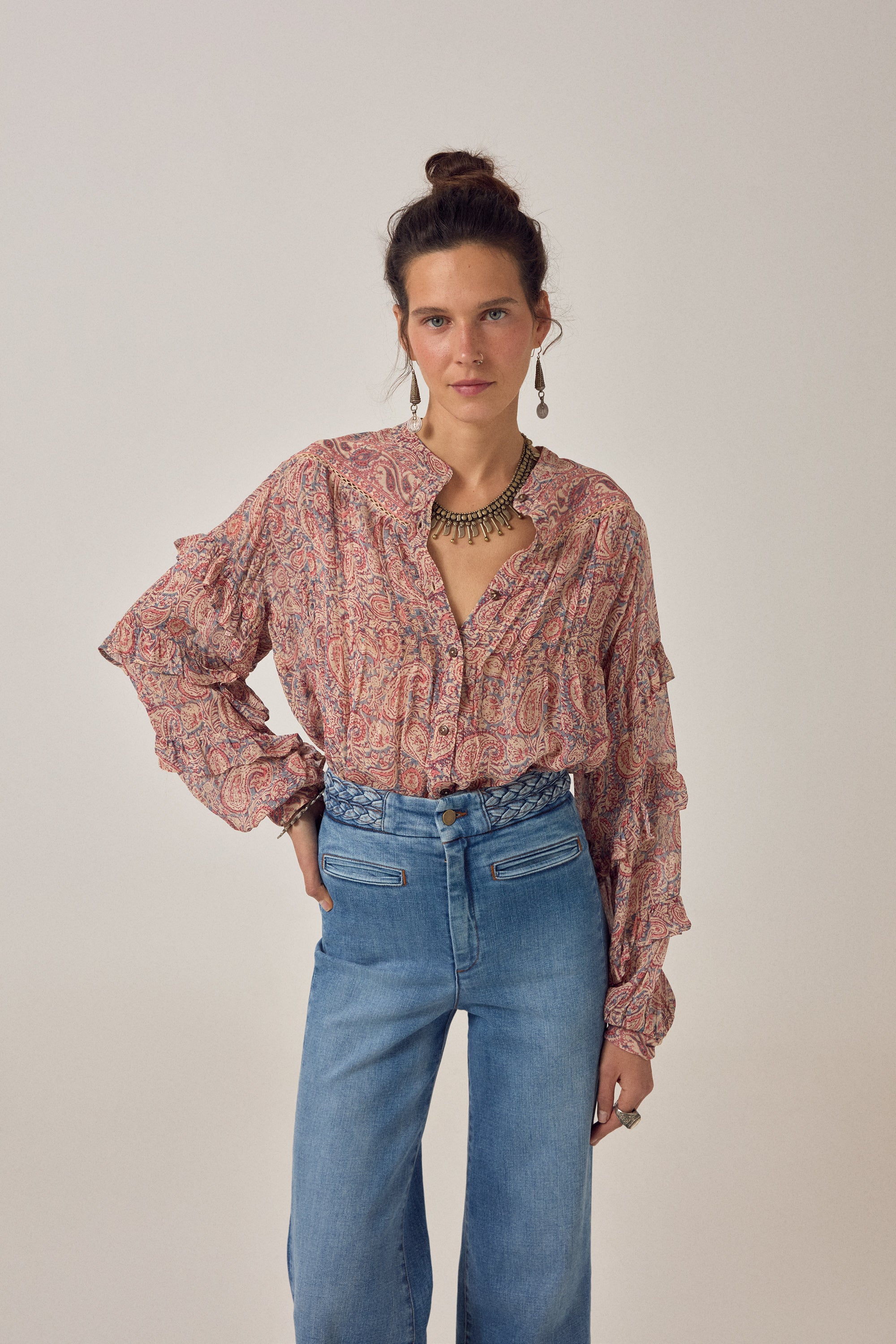 Women wearing a  floral patterned blouse and blue jeans on a plain background
