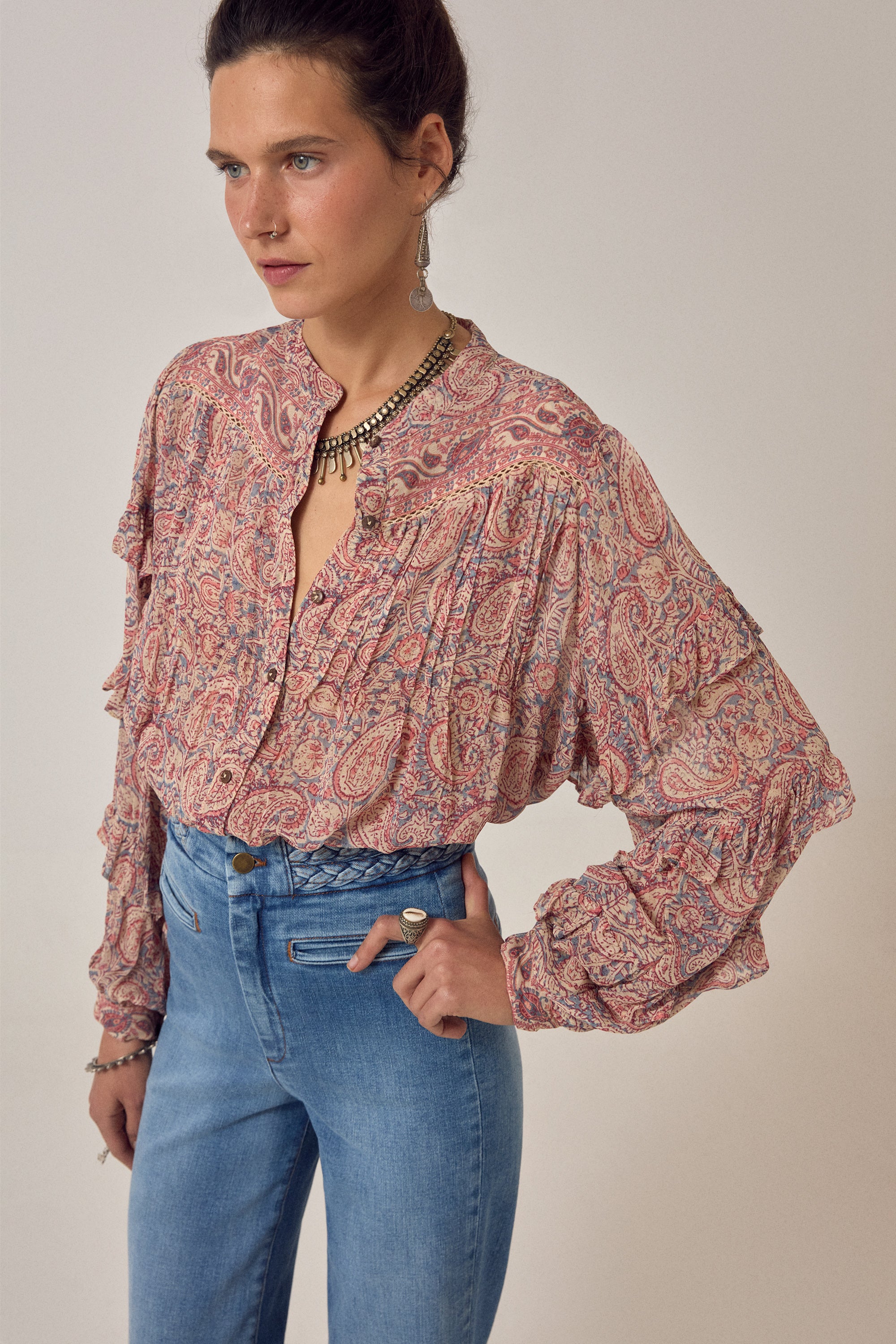Women wearing a  floral patterned blouse and blue jeans on a plain background