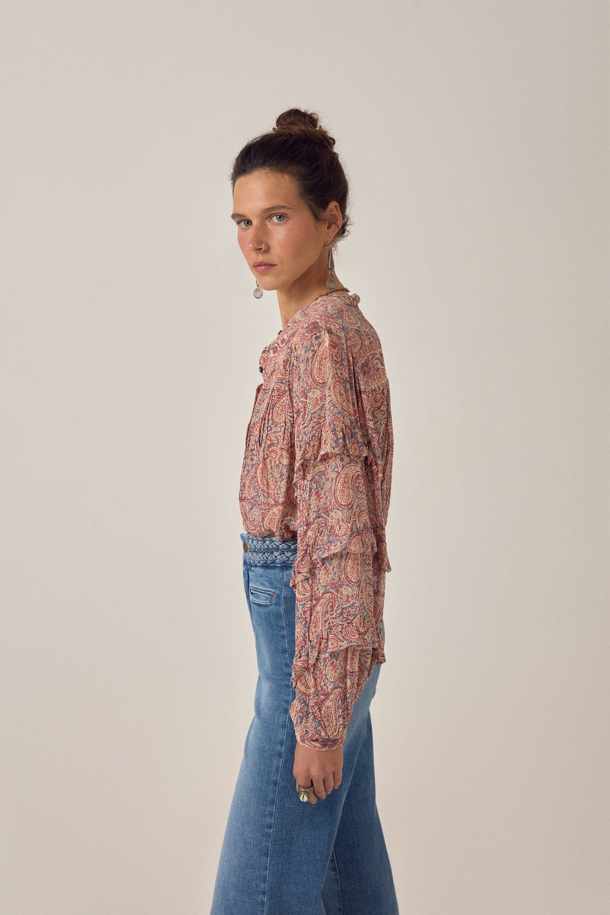 Women wearing a  floral patterned blouse and blue jeans on a plain background