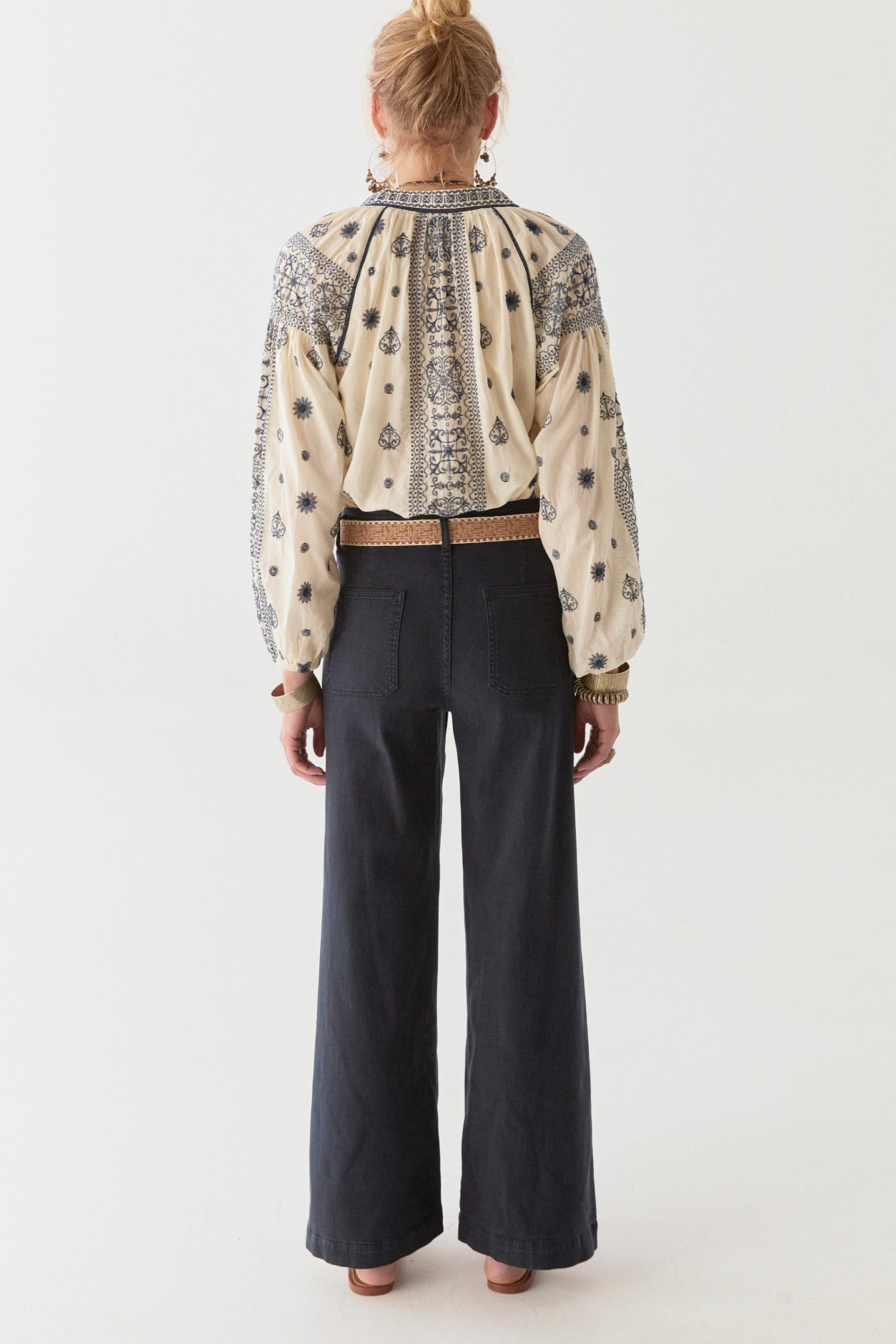 Model wearing navy wide leg pant and cream and navy cotton blouse on a white background.  Paired with tan sandals. 