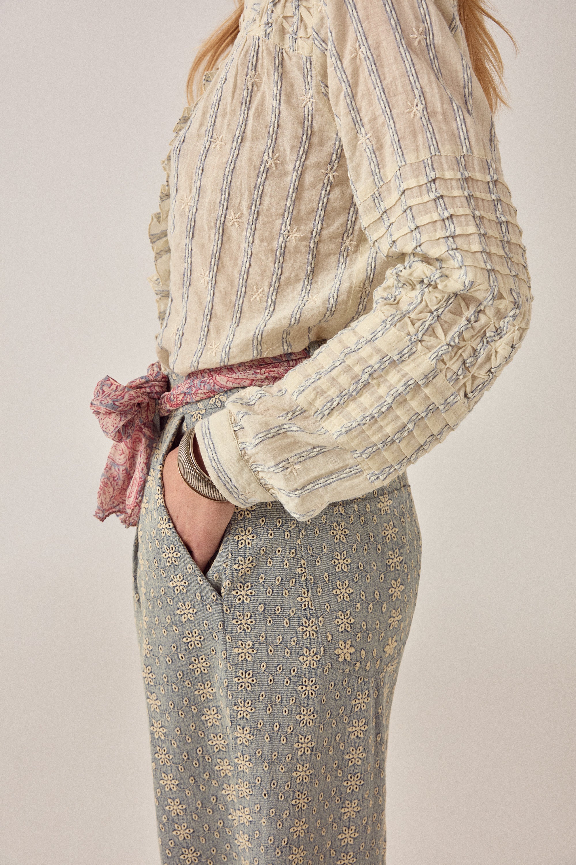 Woman wearing a beige patterned shirt with a plain background