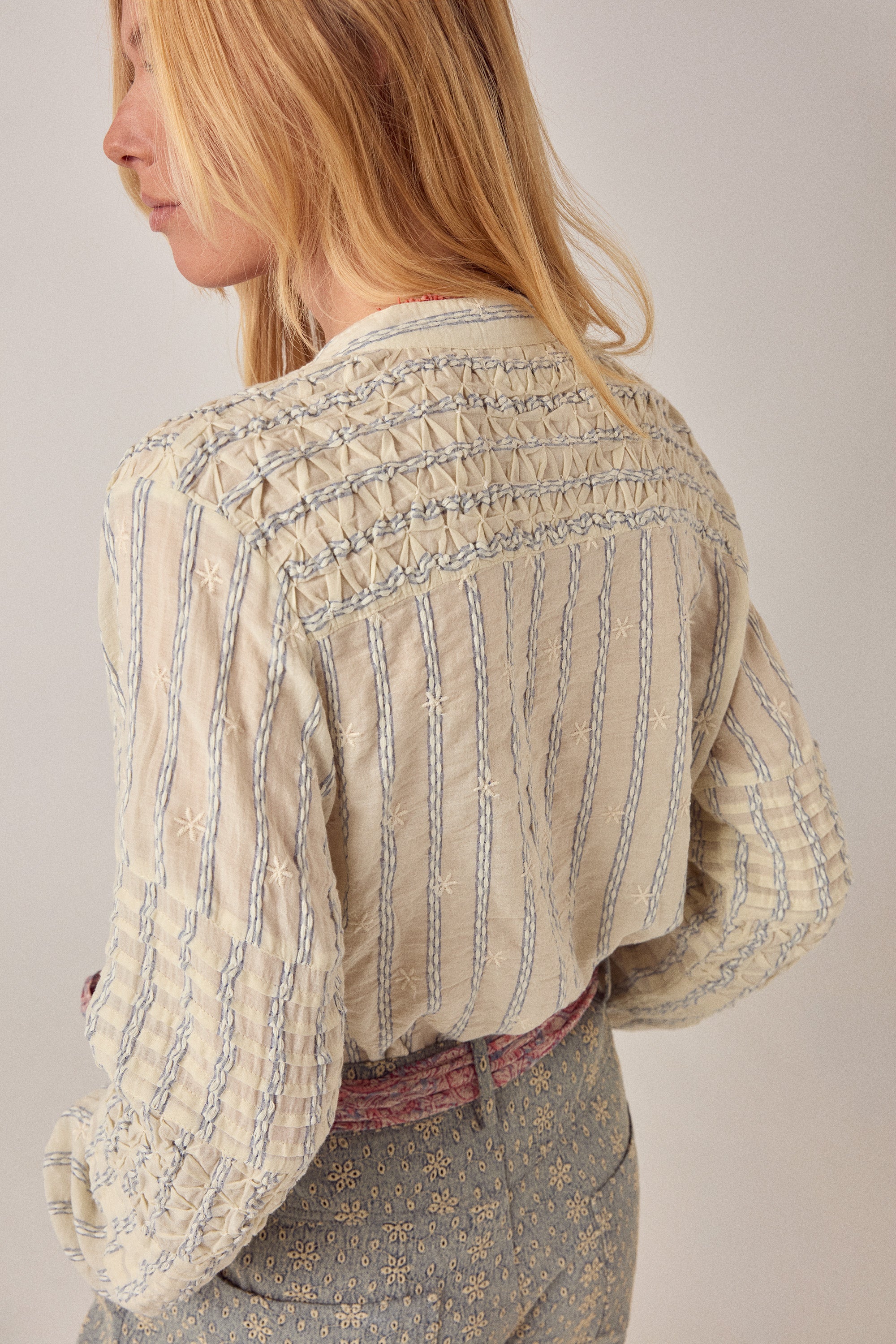 Woman wearing a beige patterned shirt with a plain background