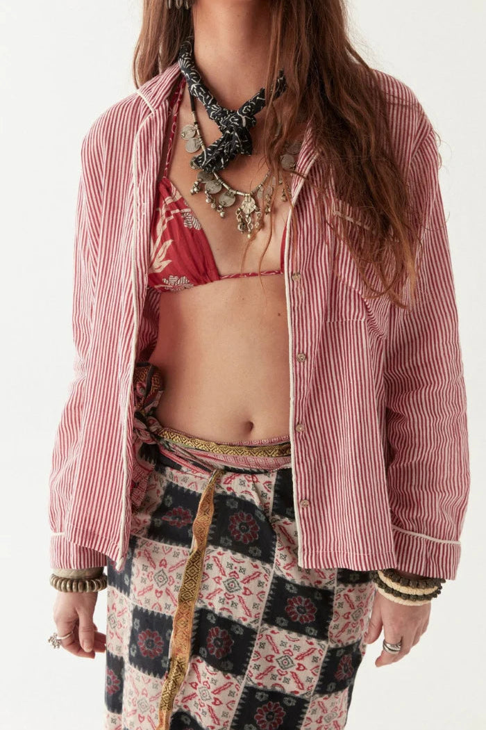 Model wearing a pink striped shirt, red bralette, and patterned pants with a white background and Goa Scarf and necklace. 