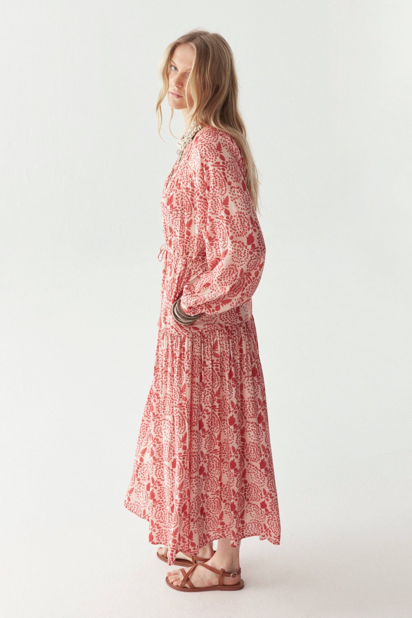Woman wearing a pink floral maxi dress dress on a white background