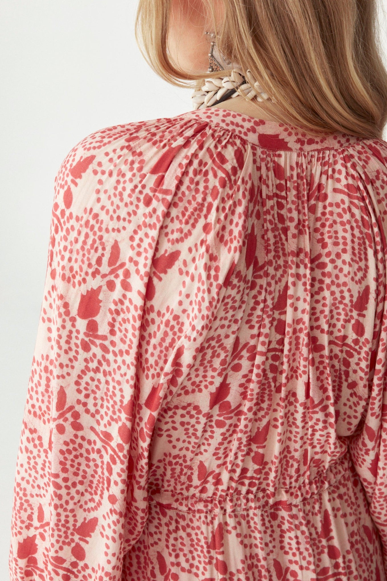 Pink and white patterned floral maxi dress by a person on a plain background. 