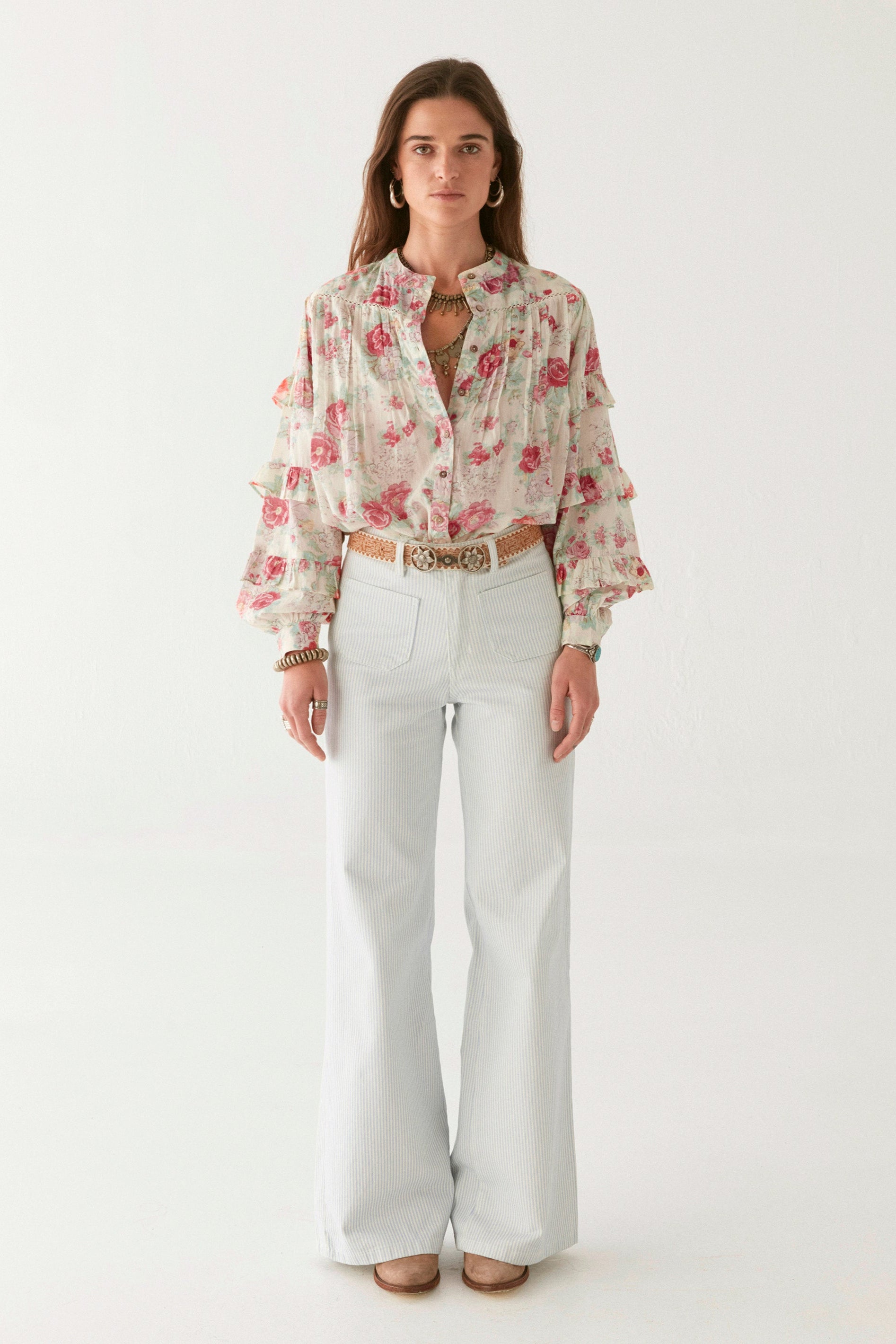 Pink floral blouse with ruffle sleeves on modal on a white background.   