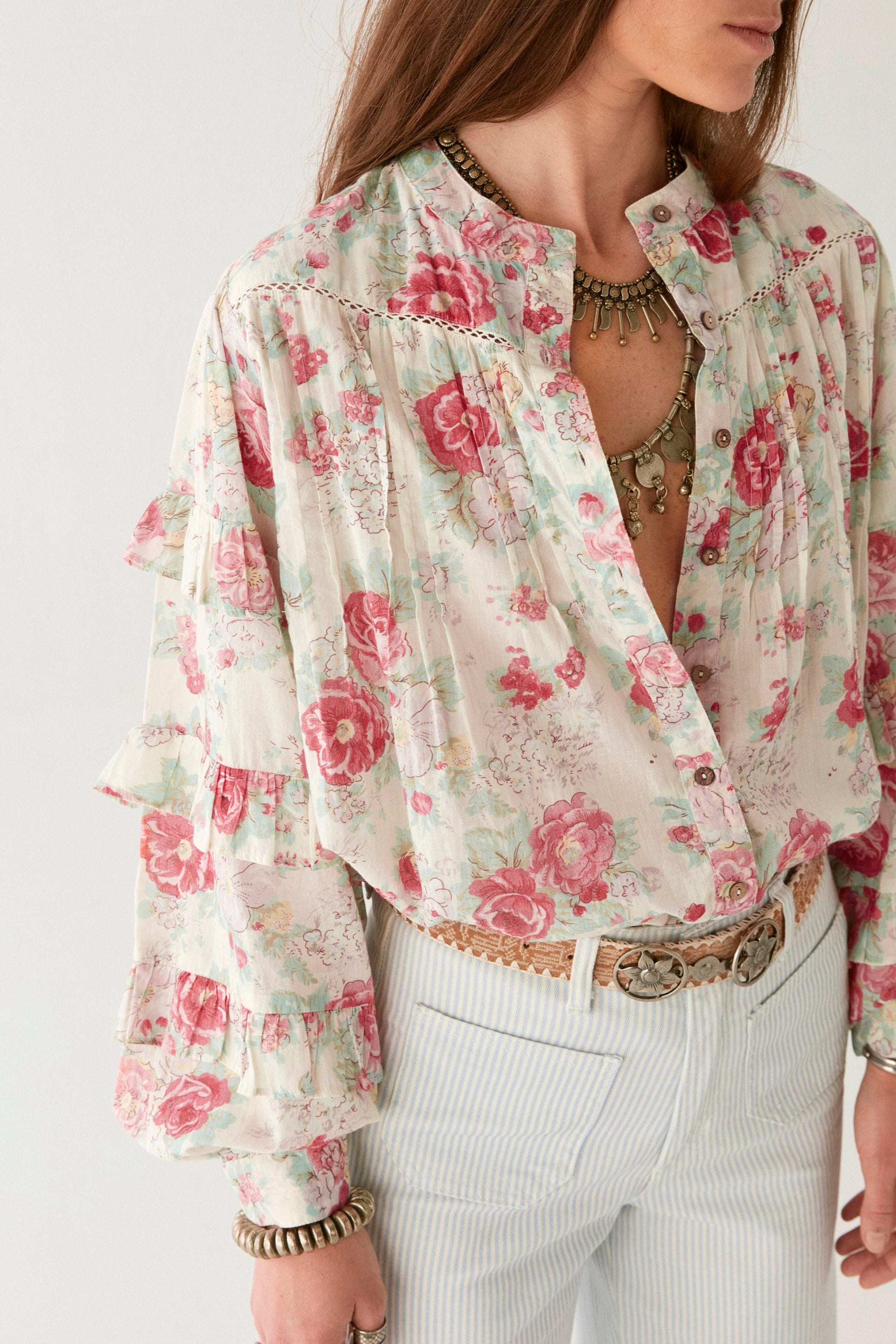 Pink floral blouse with ruffle sleeves on modal on a white background.   