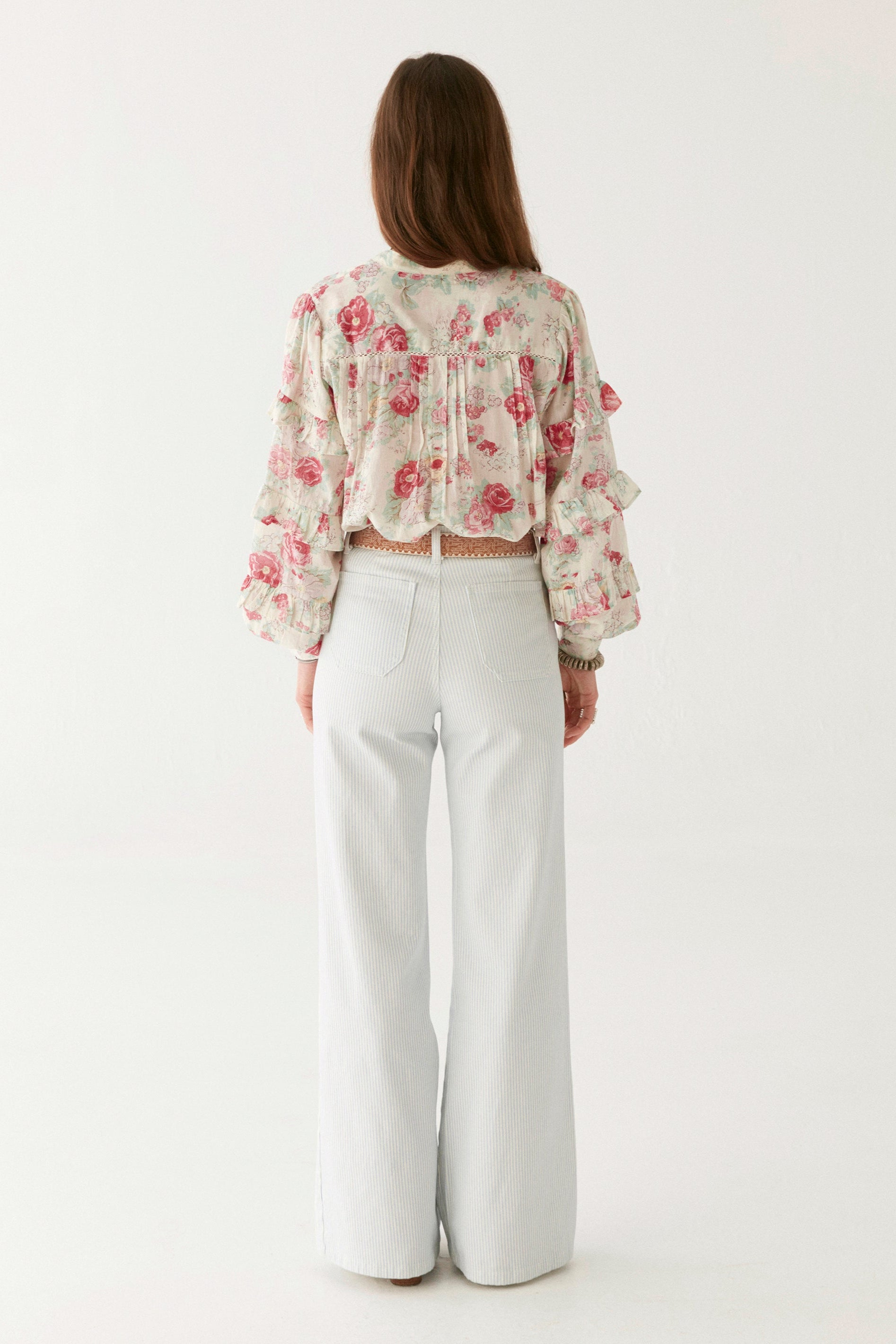 Pink floral blouse with ruffle sleeves on modal on a white background.   