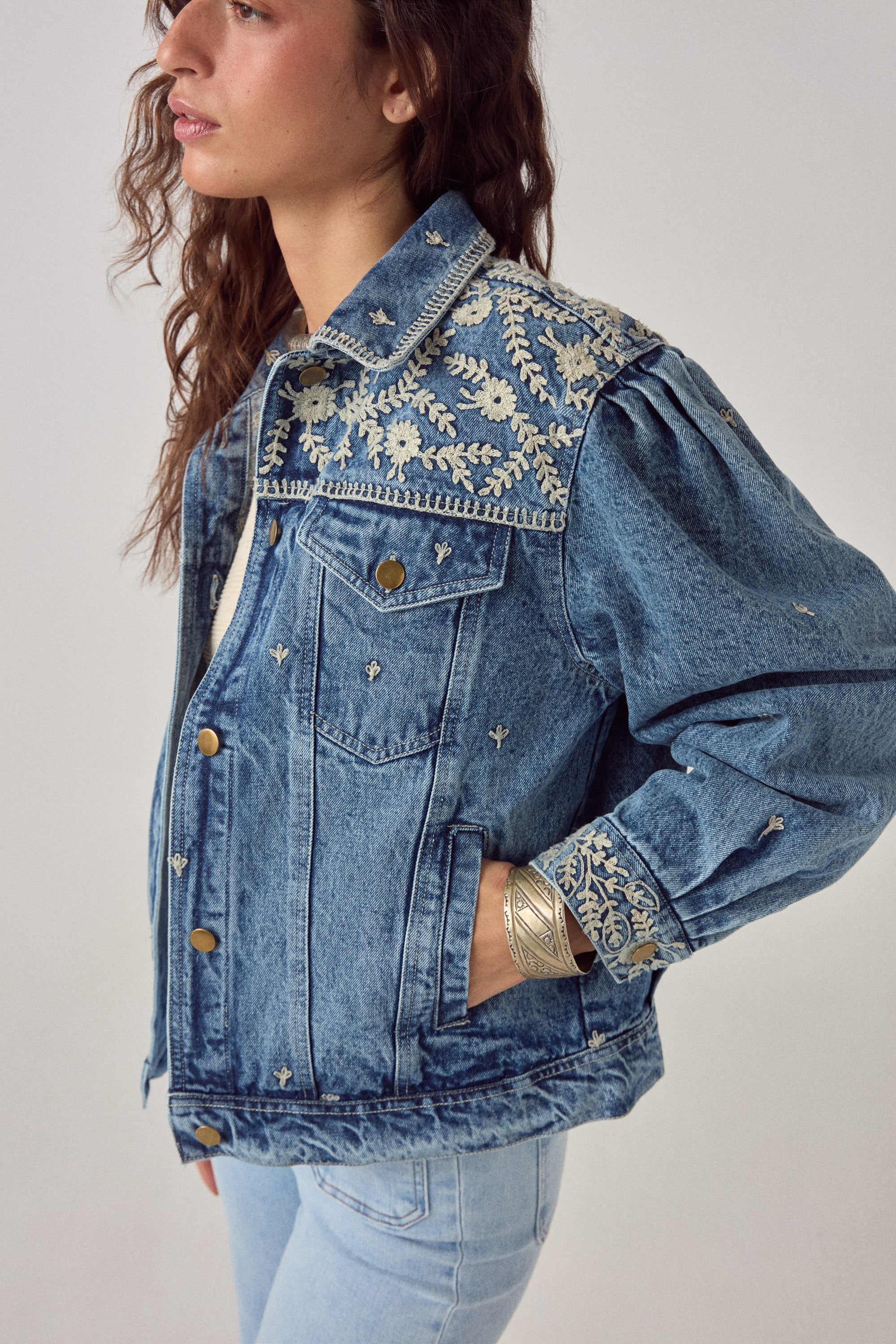 Denim jacket with floral embroidery on a plain background