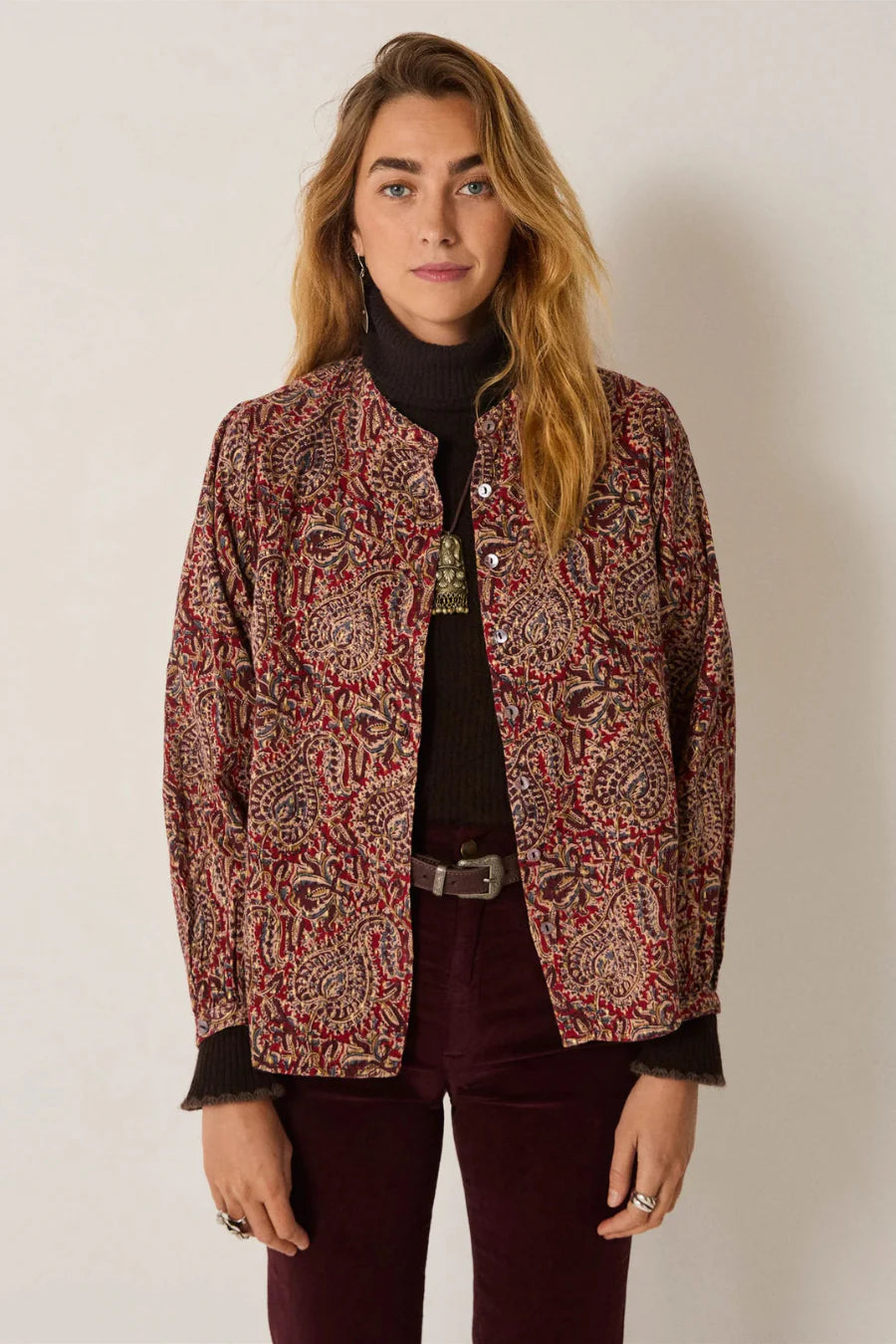 Woman wearing a patterned jacket against a plain background