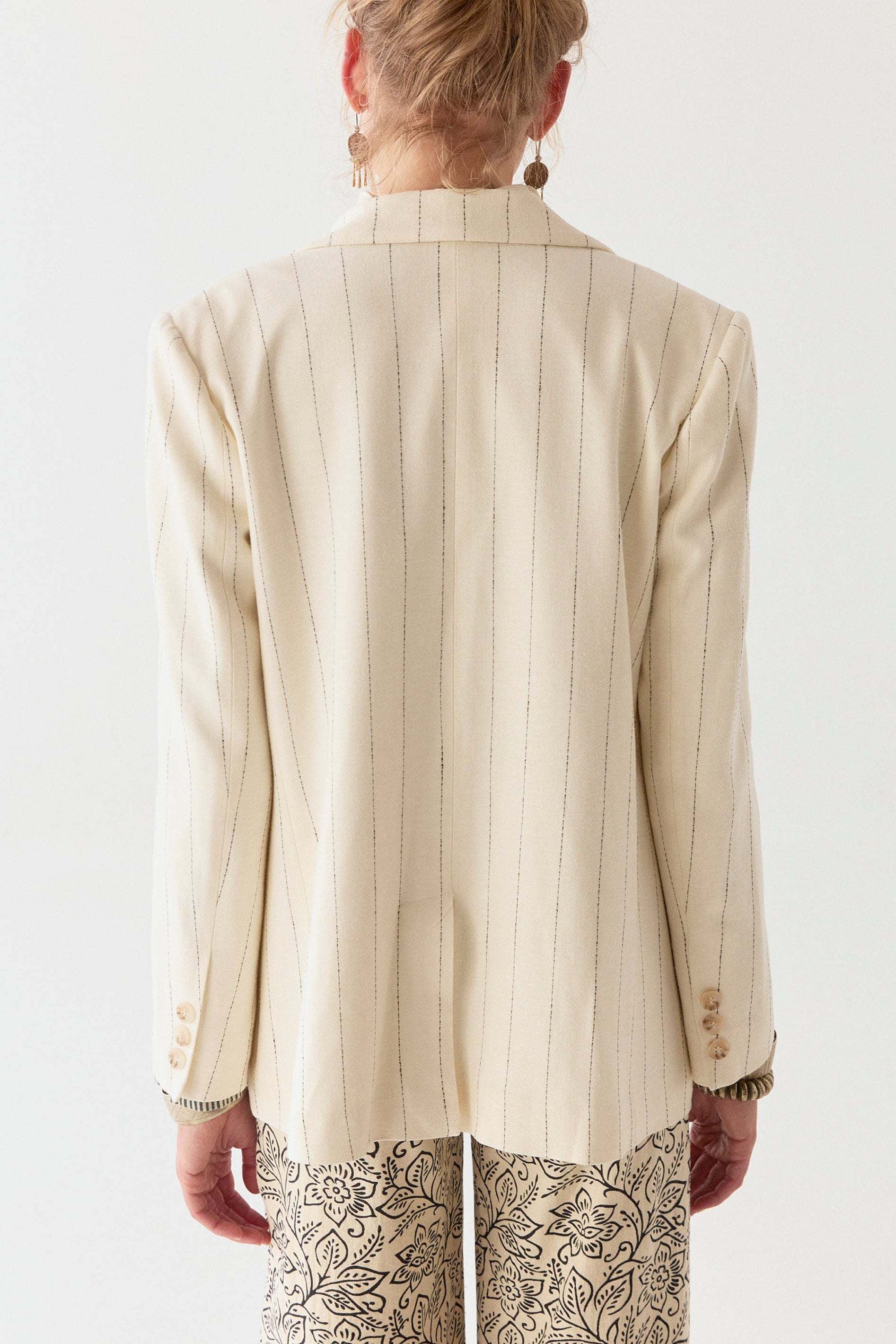 Model wearing linen cotton blend blazer in cream with navy stripe on a white background. 
