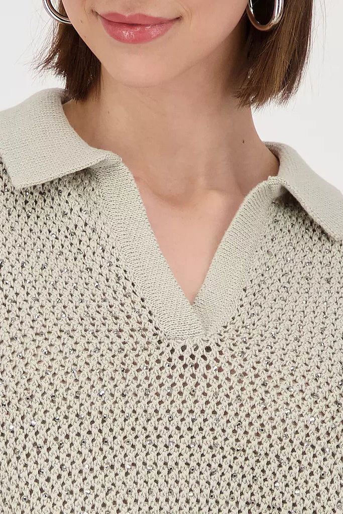 Close-up of a person wearing a textured beige sweater with a collar.