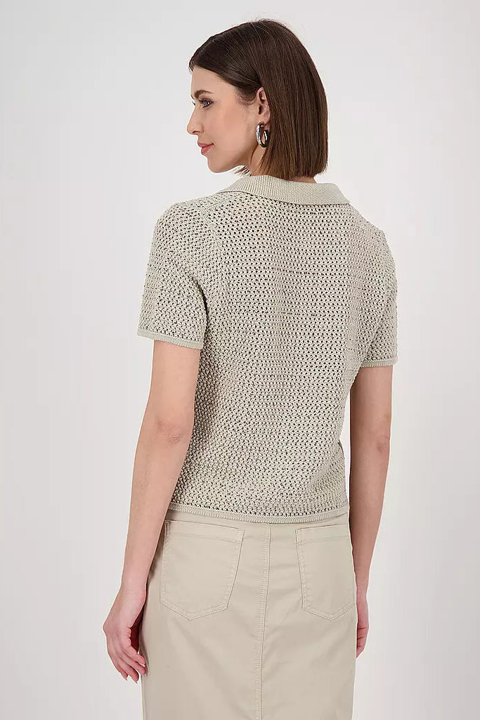 Woman wearing a textured beige knitted polo top and beige skirt on a white background